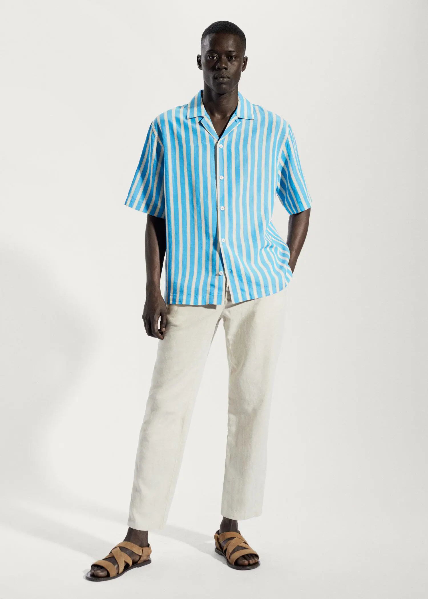 Mango Striped cotton linen shirt. a man wearing a blue and white striped shirt and white pants. 