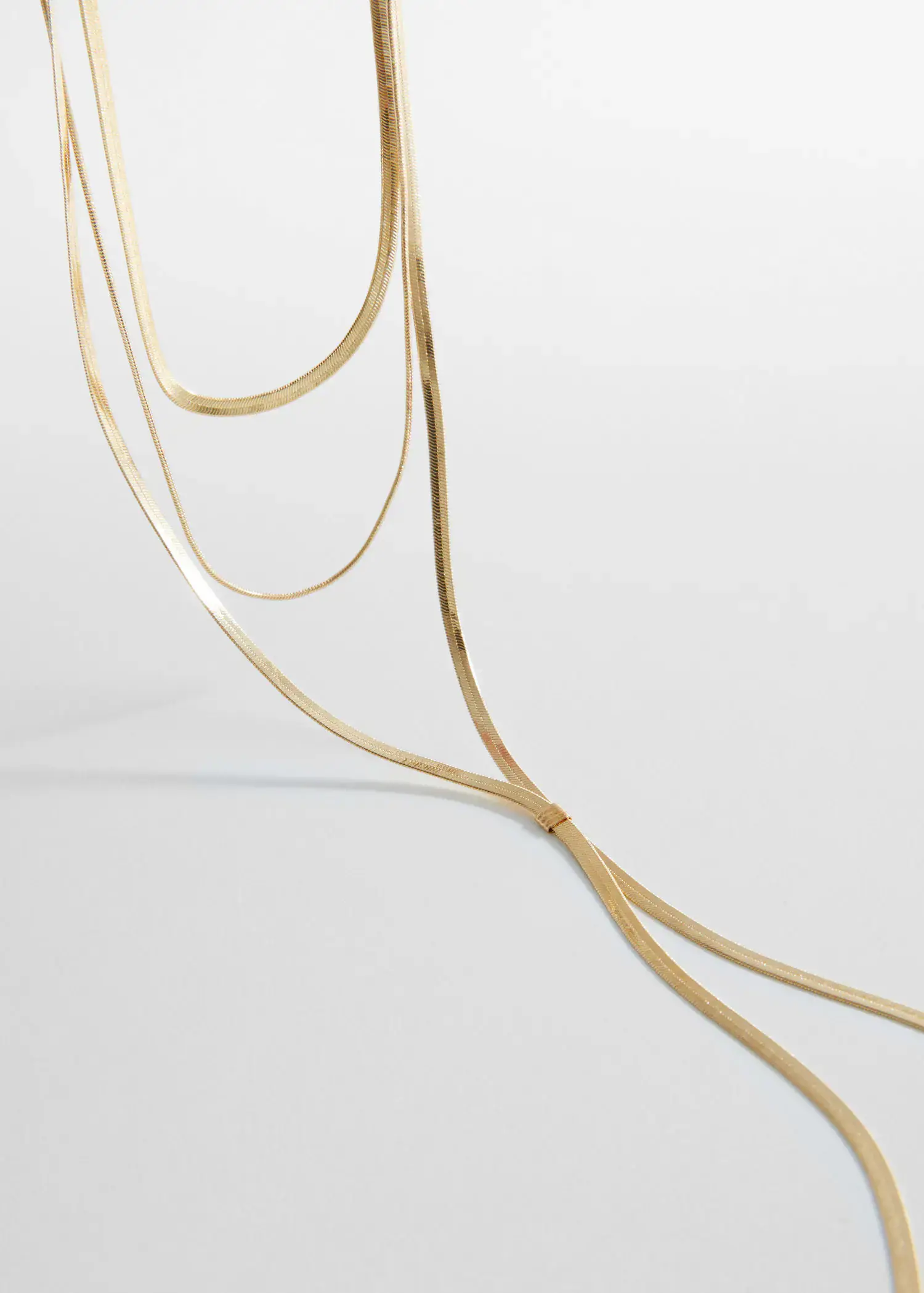 Mango Long triple necklace. a close-up of a string of gold chains. 