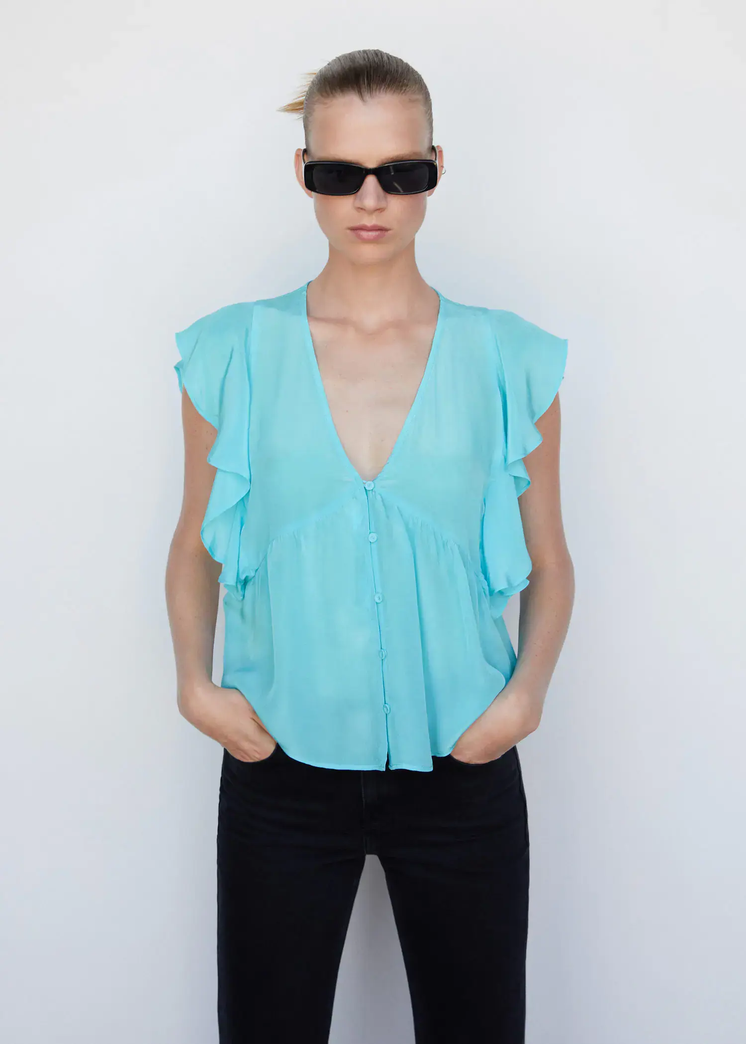 Mango Ruffled blouse. a woman wearing sunglasses and a light blue top. 