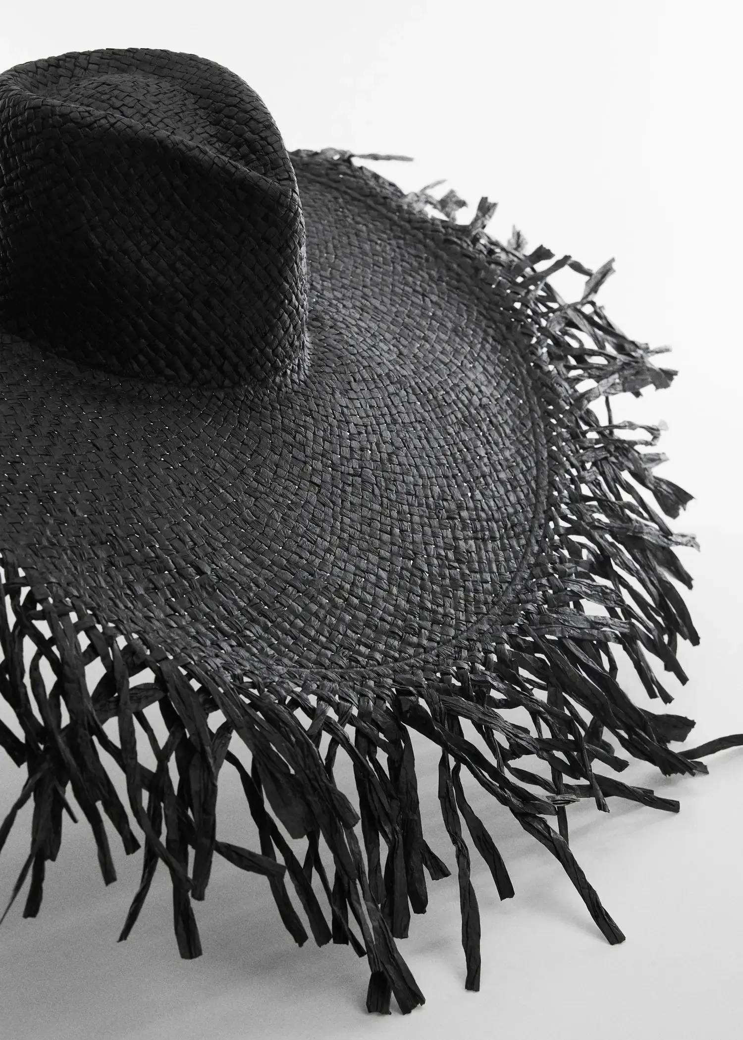Mango Natural fiber maxi hat. a close-up of a black straw hat with fringes 