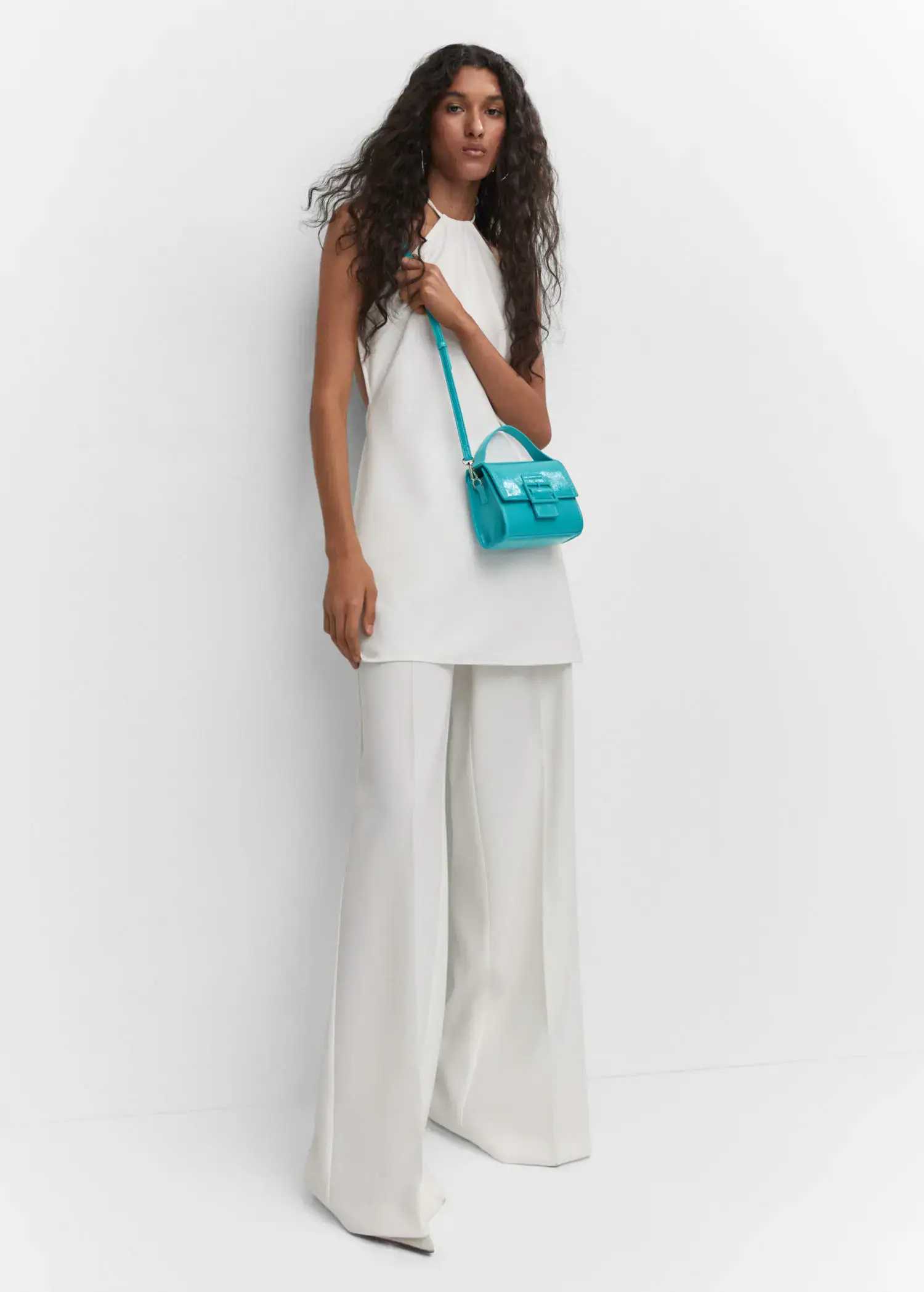 Mango Buckled flap bag. a woman holding a blue purse while standing next to a wall. 