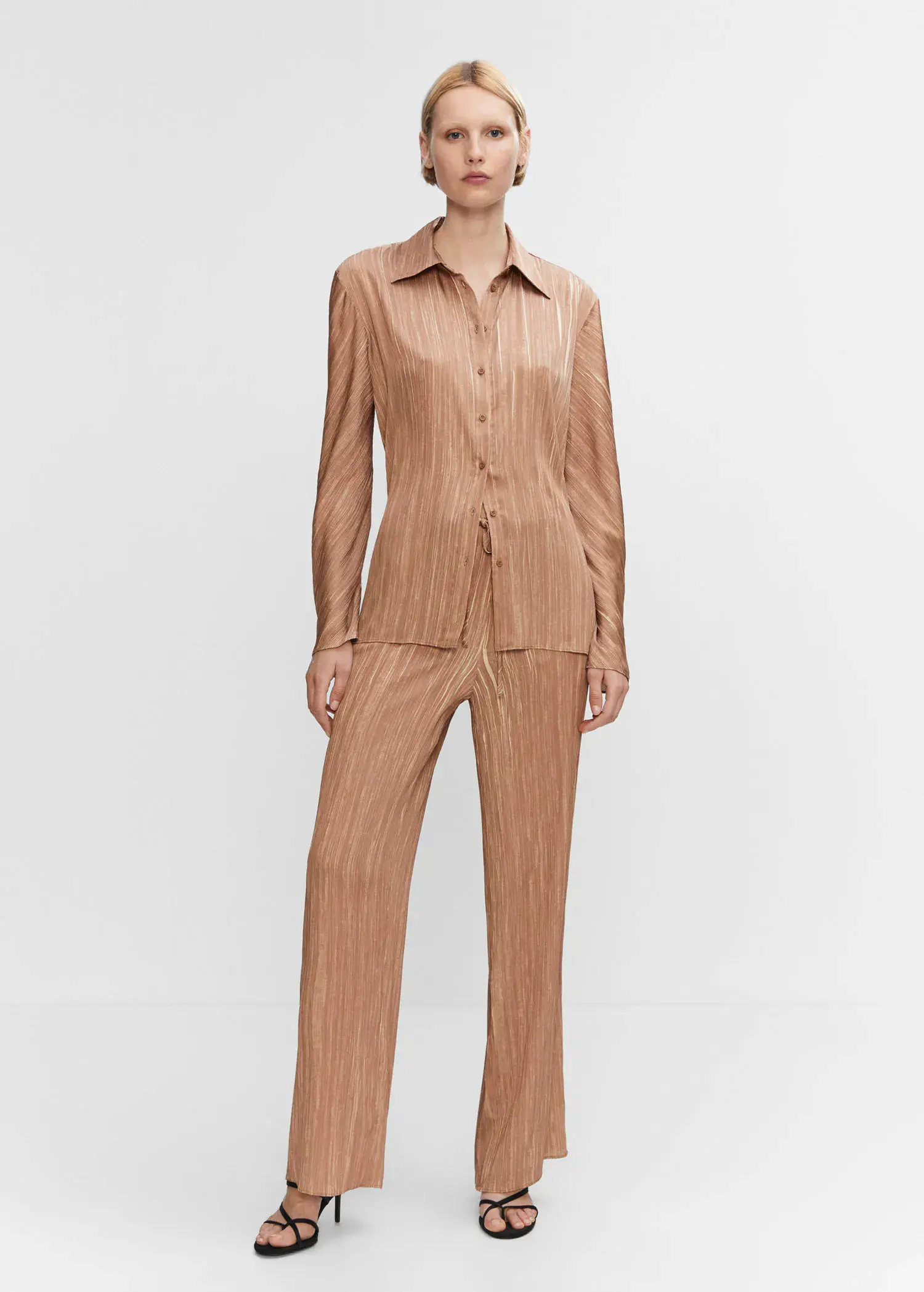 Mango Satin pleated shirt. a woman in a tan suit standing in front of a white wall. 