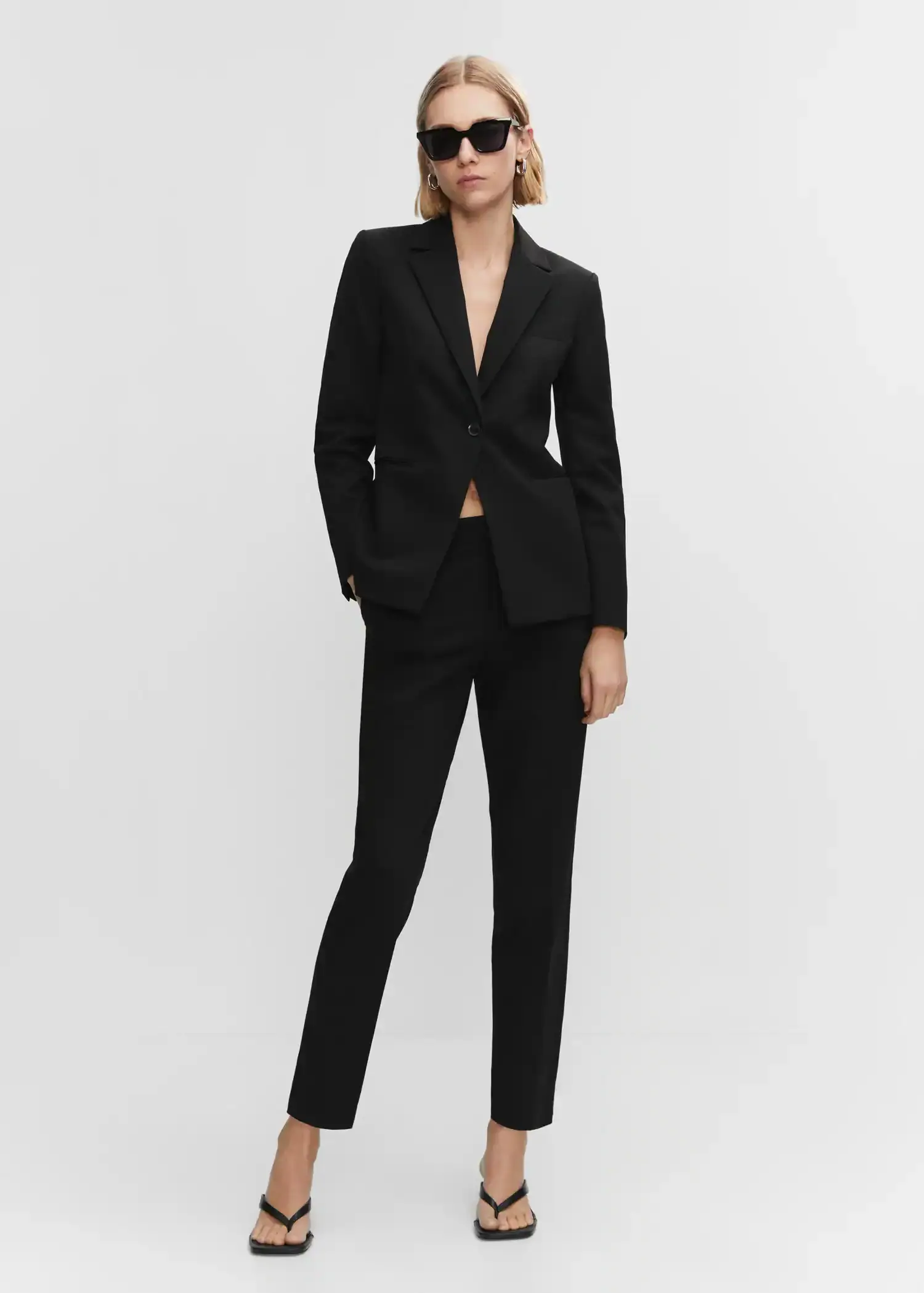 Mango Straight suit pants. a woman in a black suit standing in front of a white wall. 