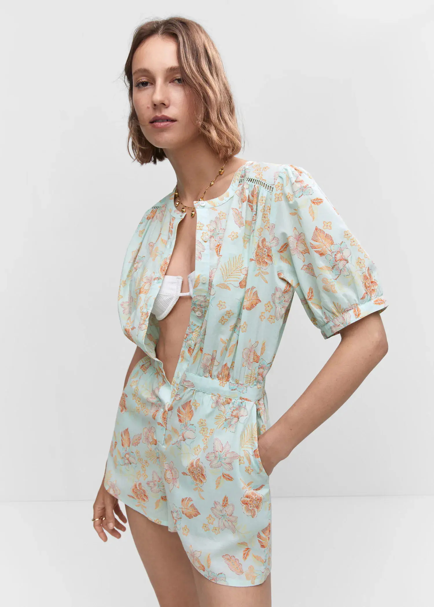 Mango Floral short jumpsuit. a woman in a floral print dress standing next to a white wall. 