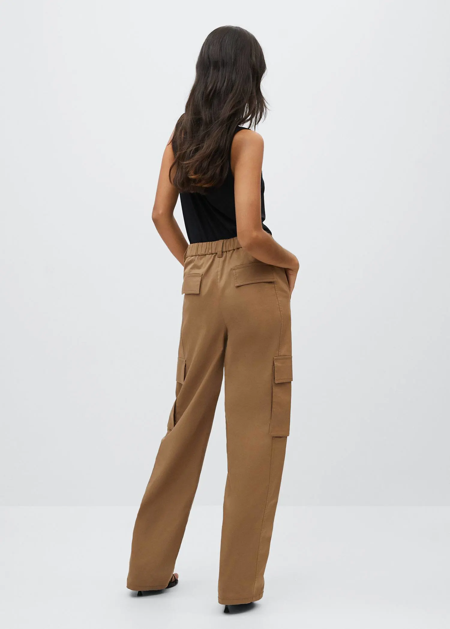 Mango Flowy strap top. a woman wearing a black top and brown pants. 