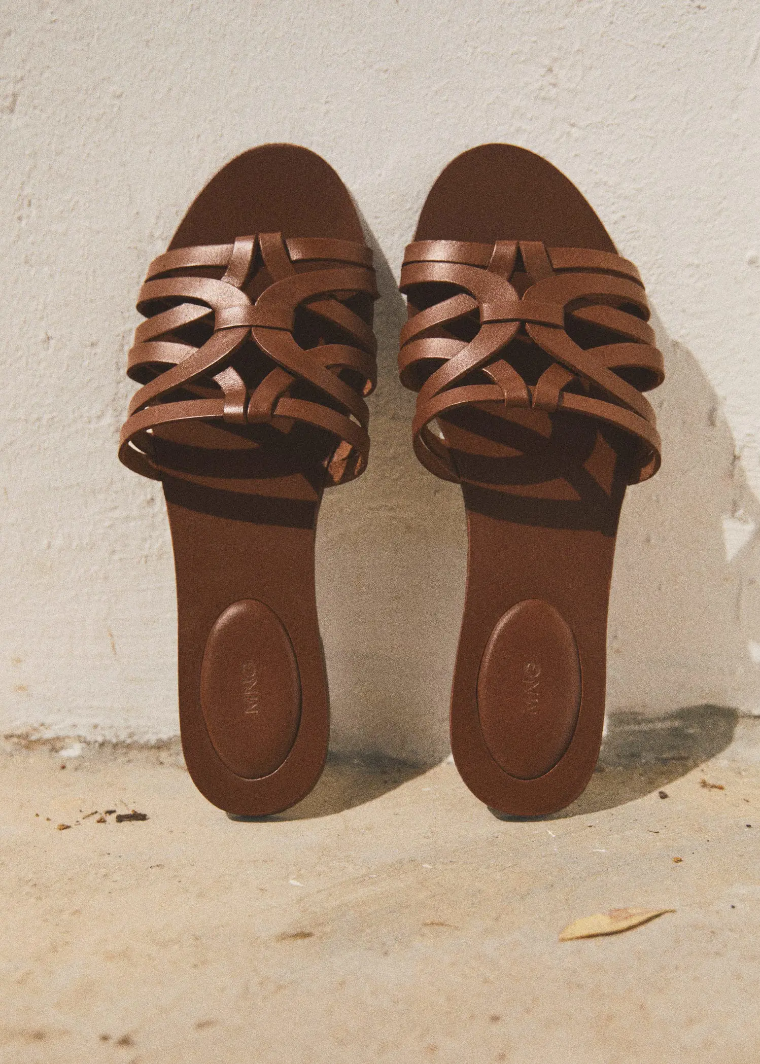 Mango Leather straps sandals. a pair of brown sandals hanging on a wall. 