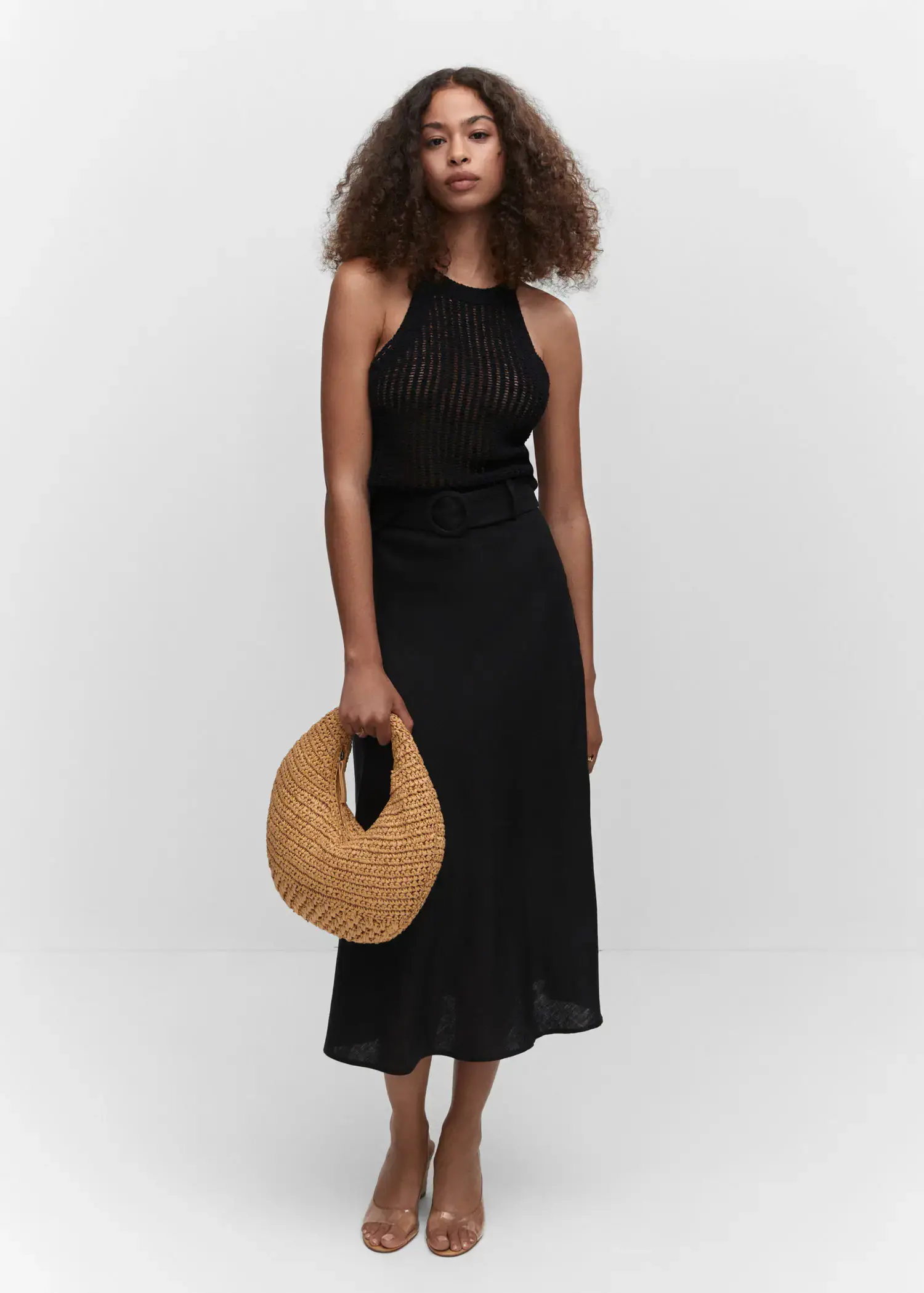 Mango Halter-neck knitted top. a woman in a black dress holding a straw bag. 