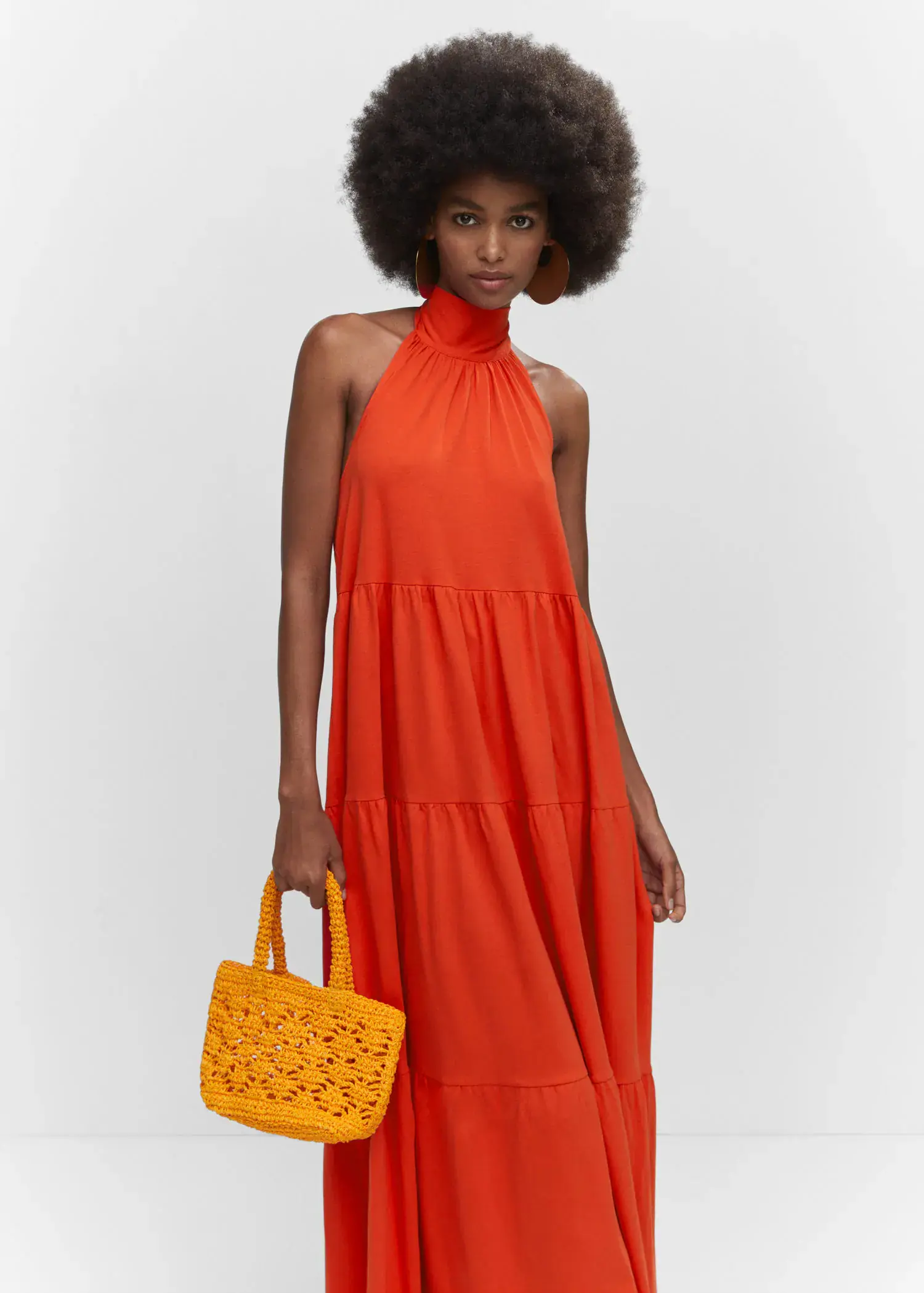 Mango Halter-neck open-back dress. a woman holding a yellow purse in front of a white wall. 