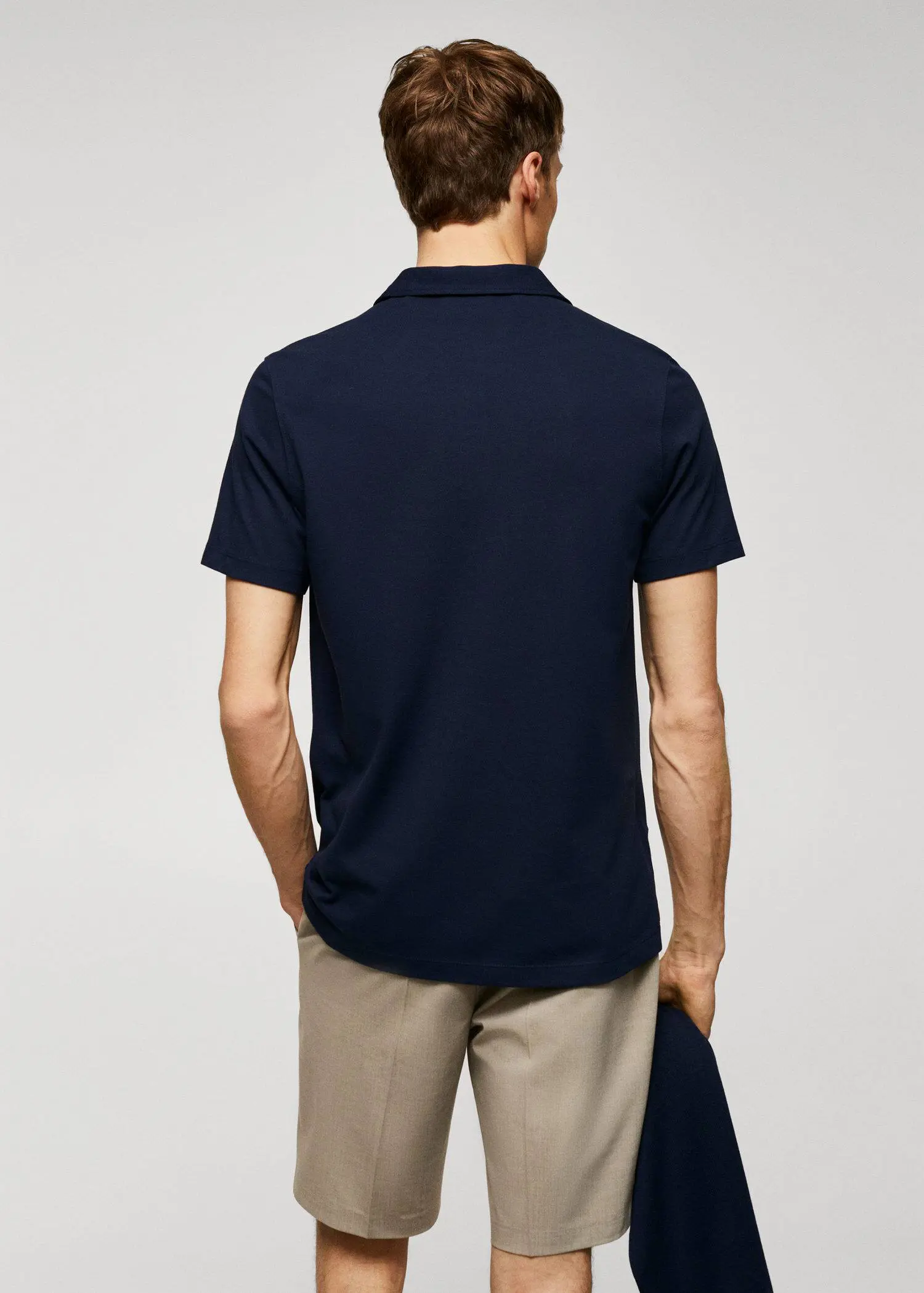Mango Slim-fit textured cotton polo shirt. a man wearing a navy blue polo shirt and khaki pants. 