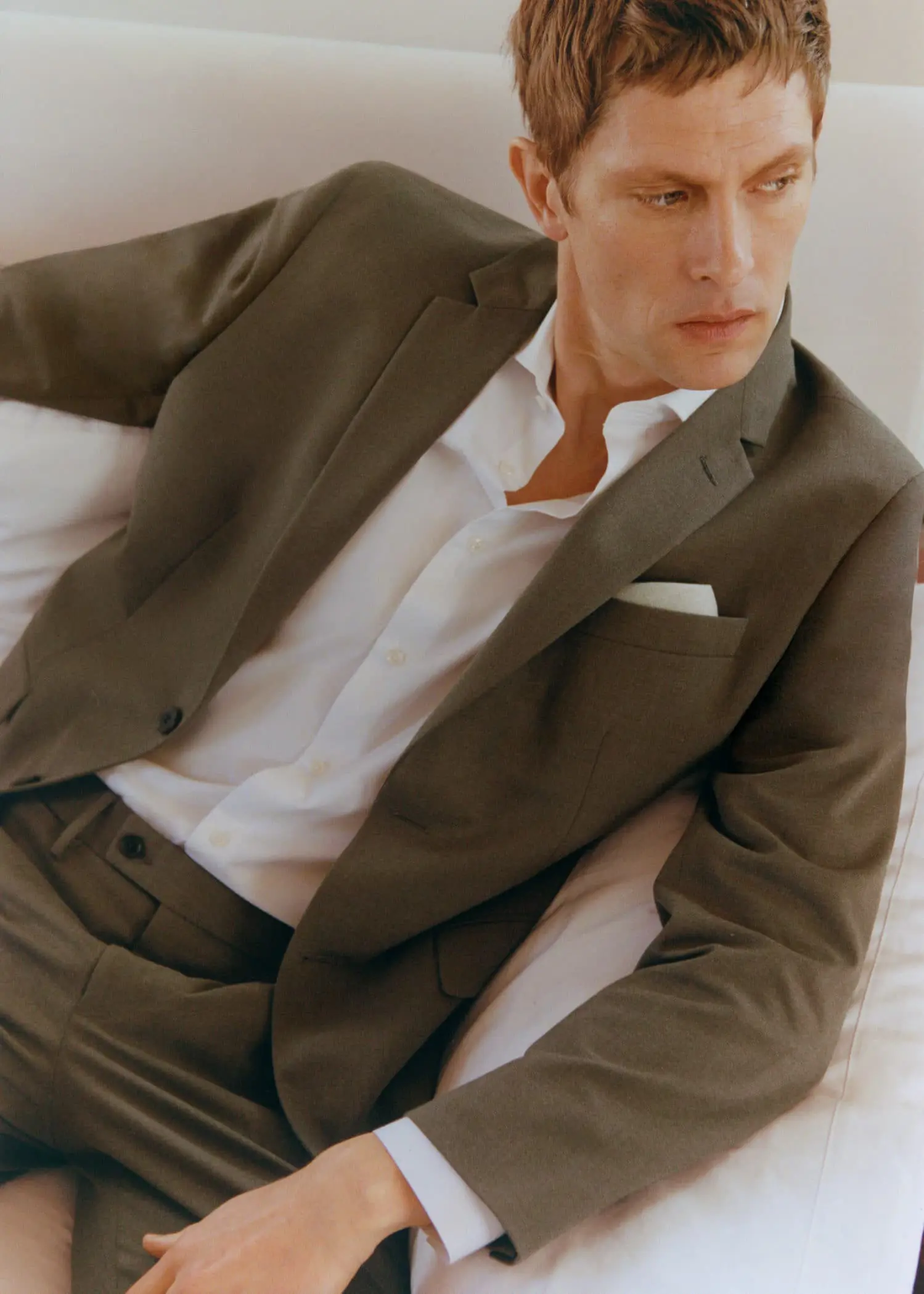 Mango Stretch fabric slim-fit suit jacket. a man wearing a suit and tie sitting on a bed. 