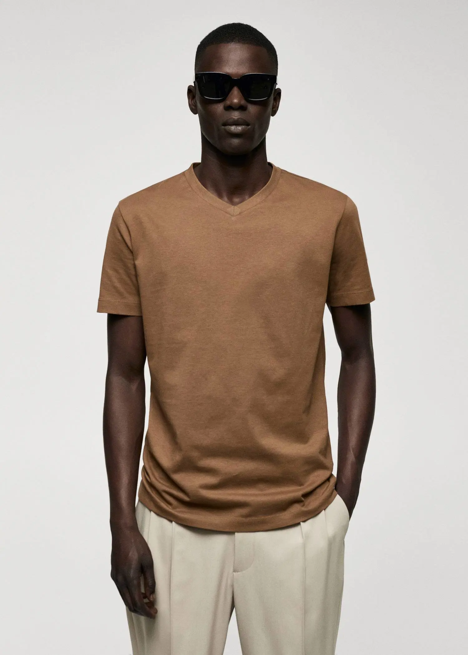 Mango Basic cotton V-neck T-shirt. a man in a brown shirt and white pants. 