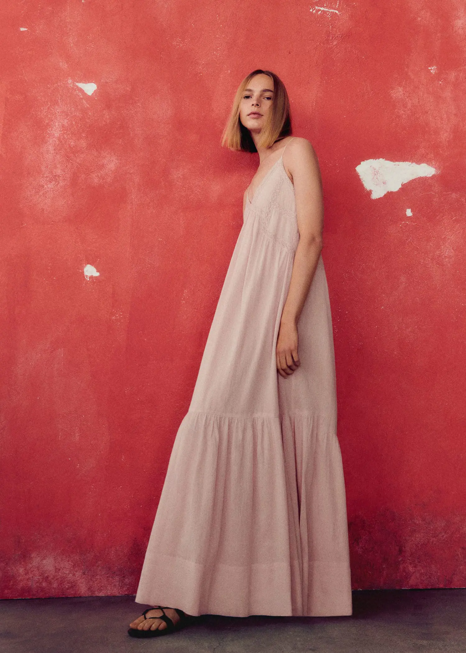 Mango Maxi-dress with lace details. a woman standing in front of a red wall. 