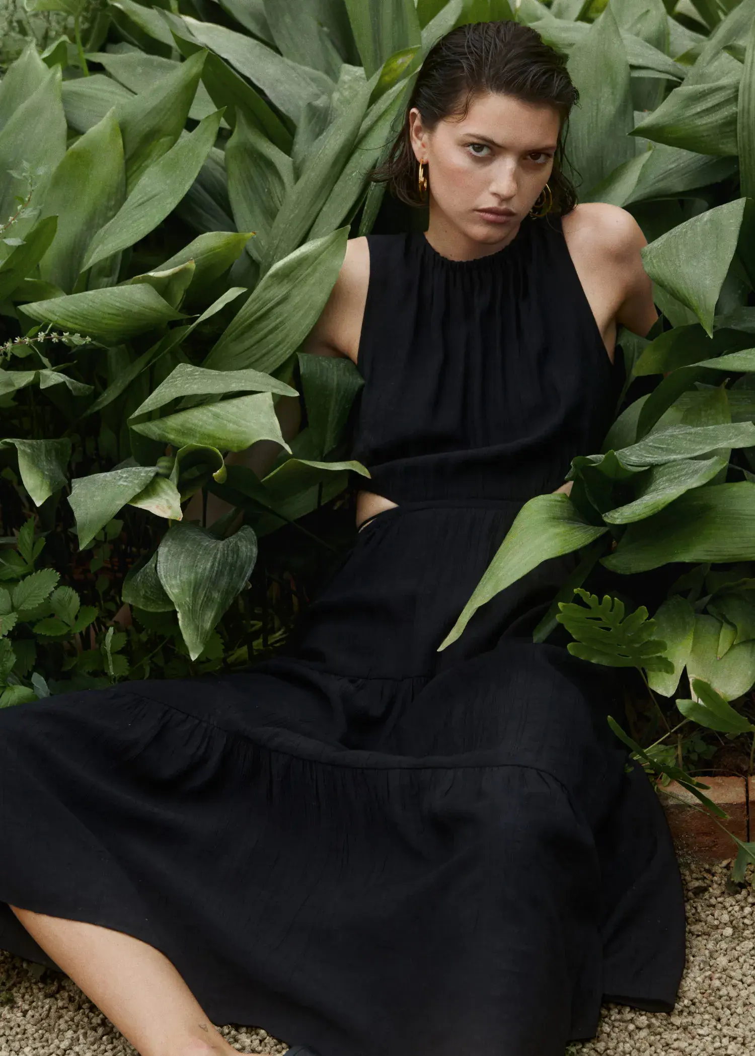 Mango Flared dress with openings. a woman in a black dress sitting in a garden. 
