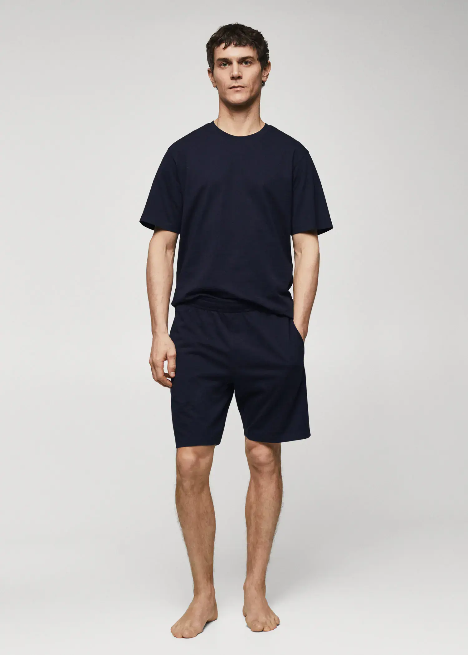 Mango Cotton pajama shorts pack. a man in black shirt and shorts standing next to a wall. 