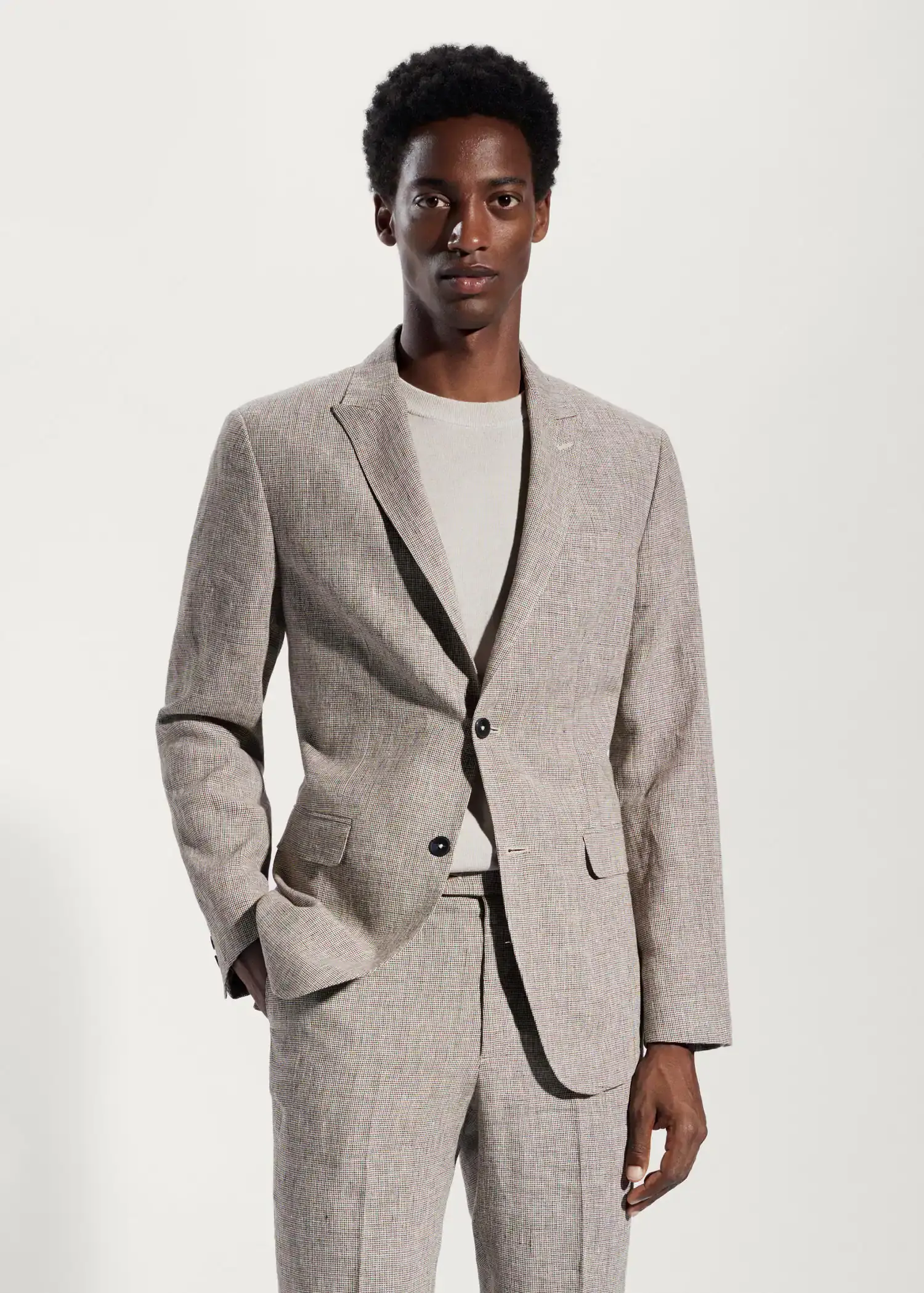 Mango Blazer suit 100% linen. a man in a suit stands in front of a white wall. 