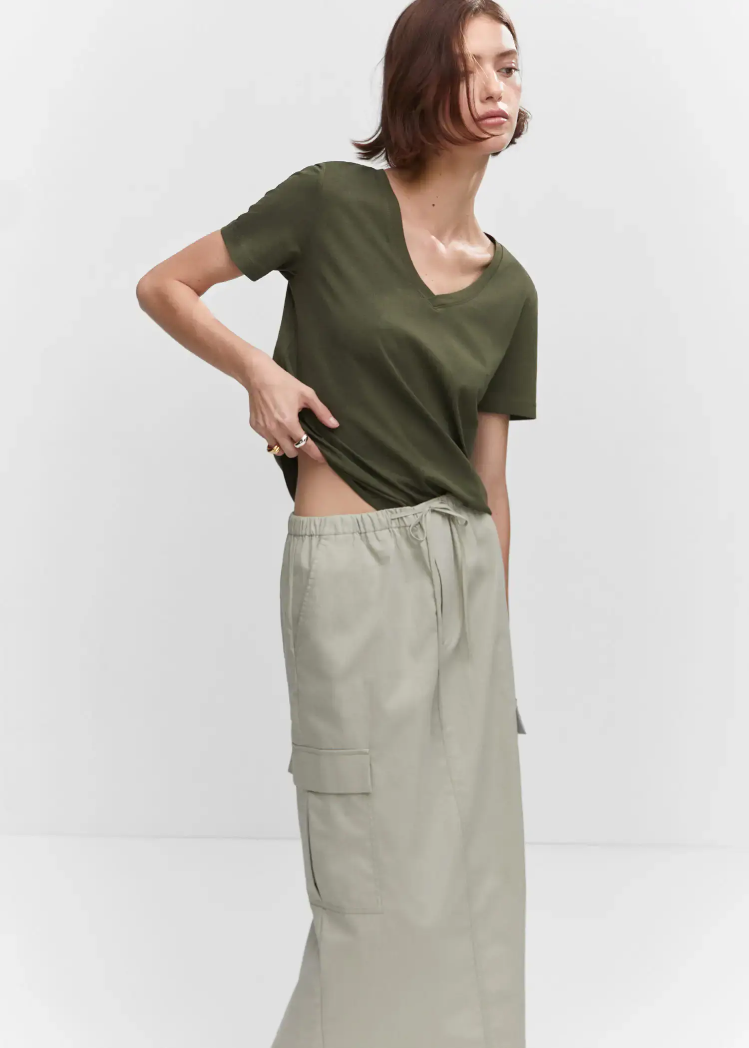 Mango V-neck cotton T-shirt. a woman wearing a green shirt and a gray skirt. 