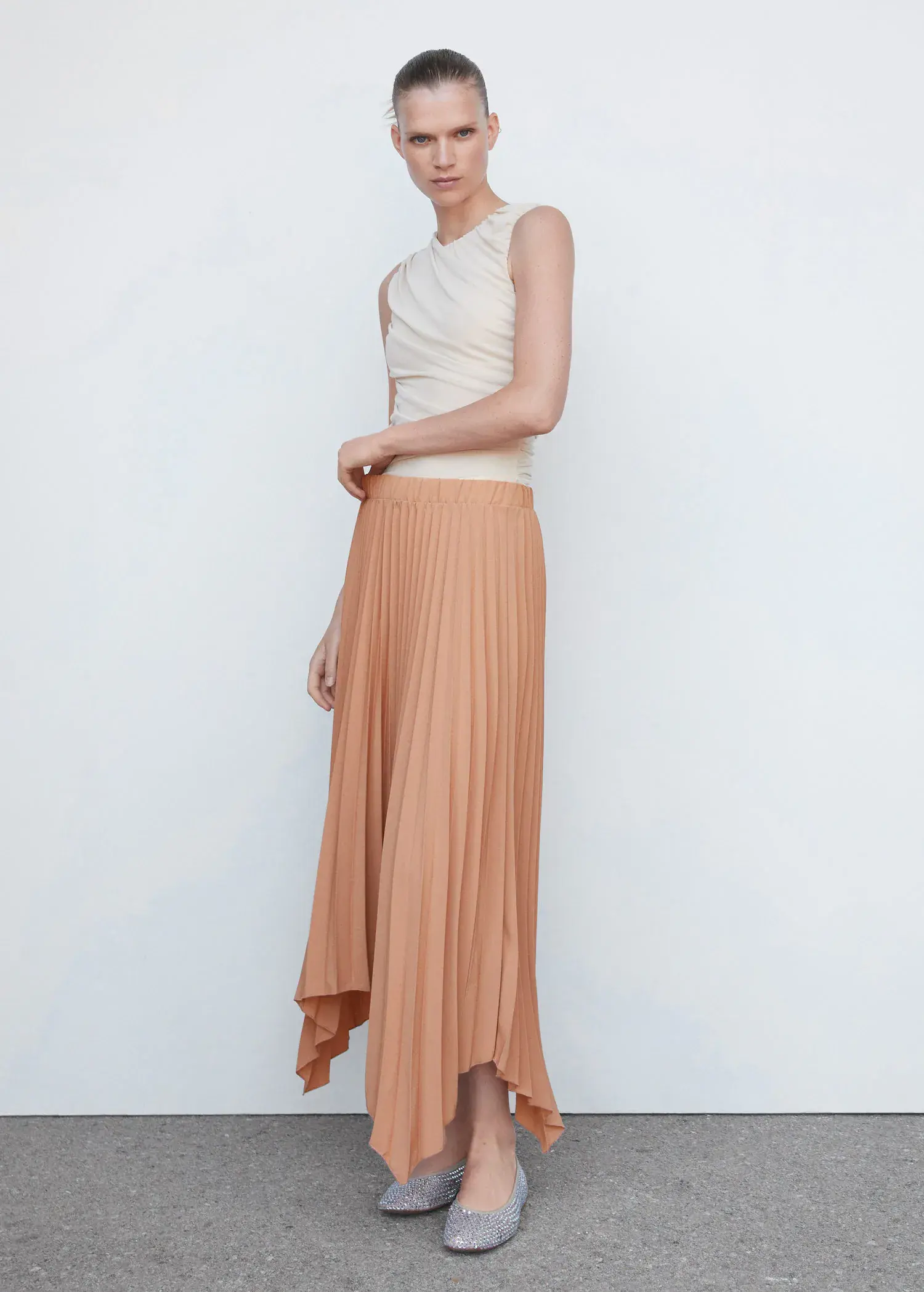 Mango Pleated asymmetric skirt . a woman standing in front of a white wall. 