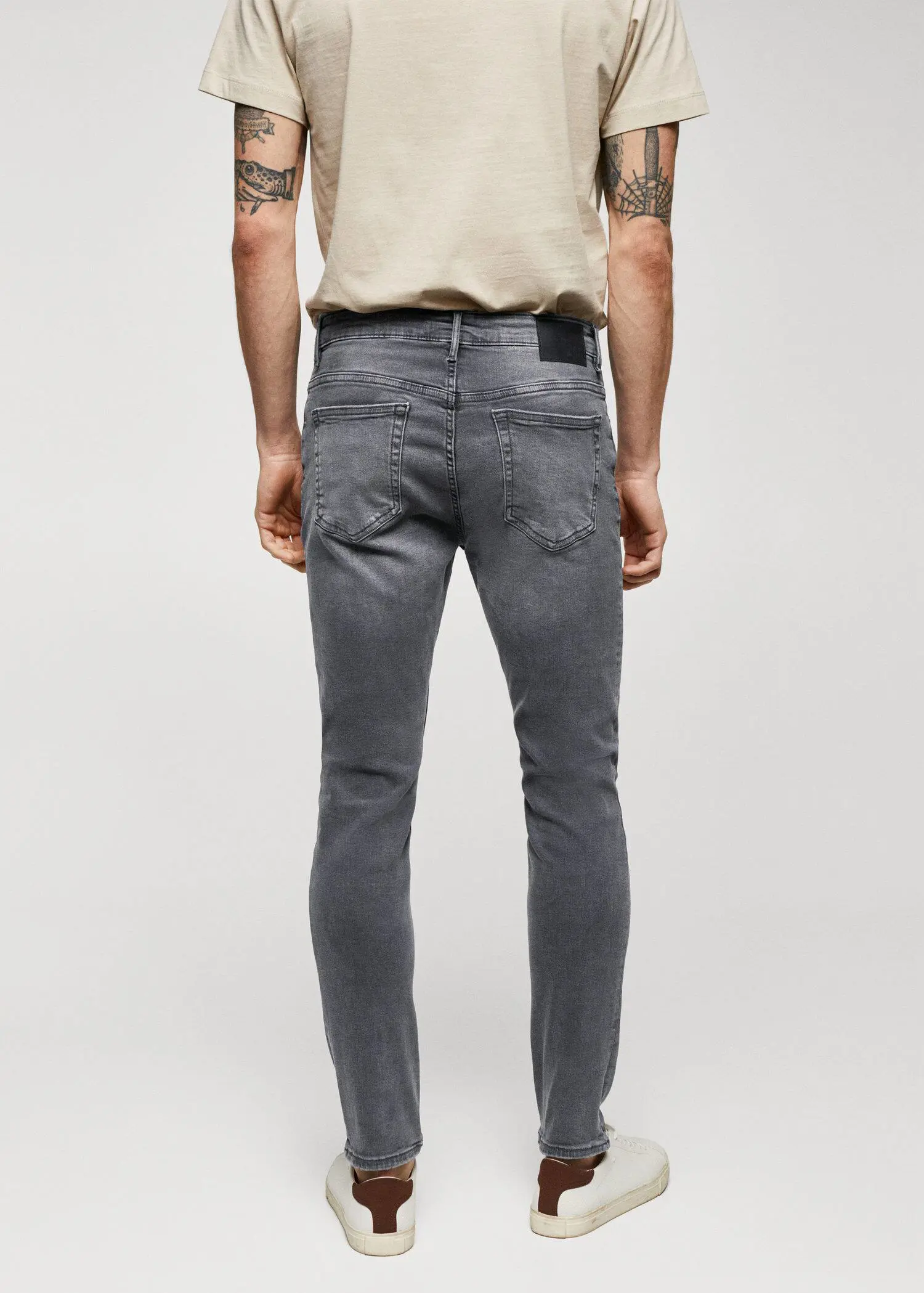 Mango Jude skinny-fit jeans. a man wearing grey jeans and a beige shirt. 