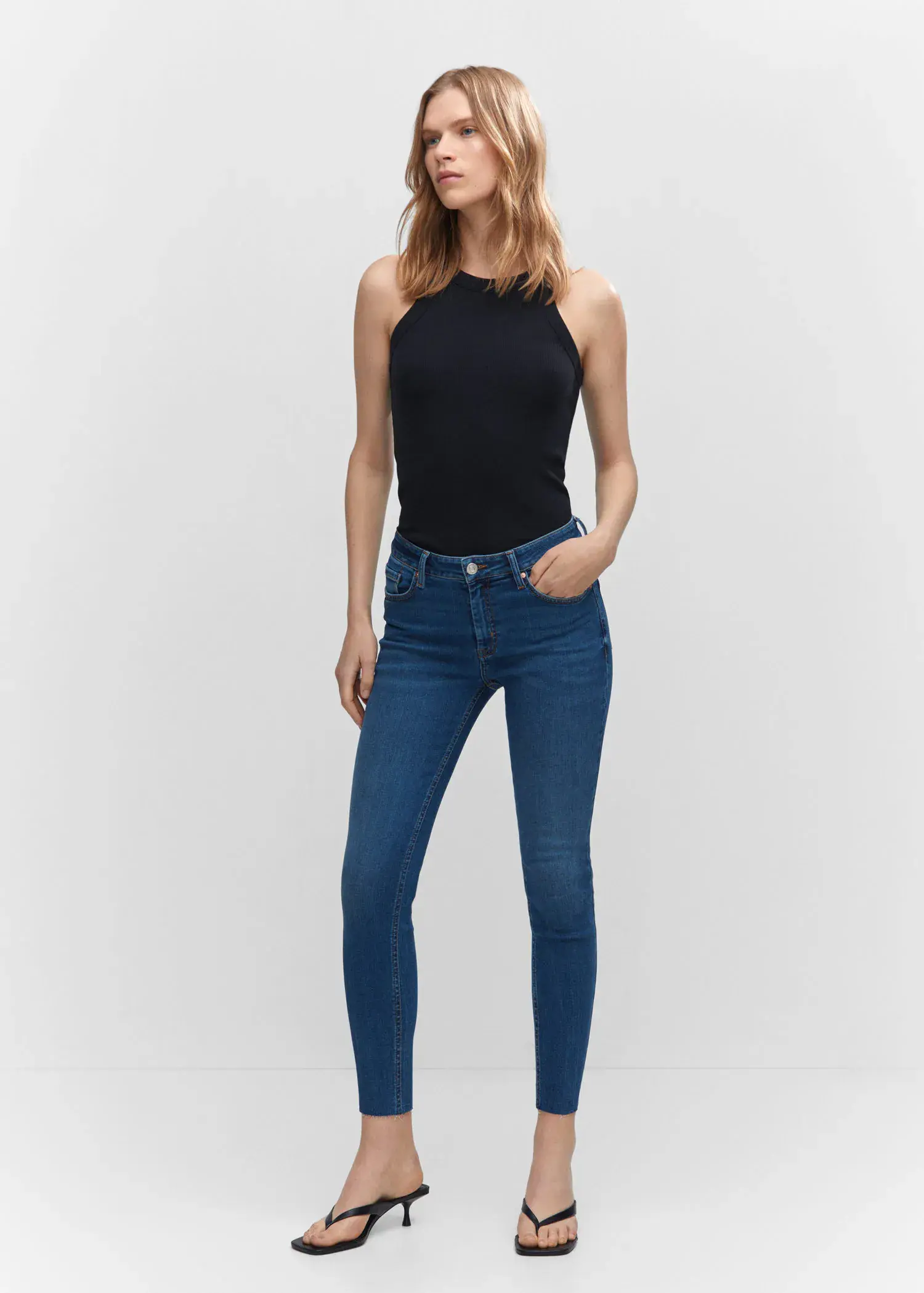 Mango Skinny cropped jeans. a woman wearing a black top and blue jeans. 