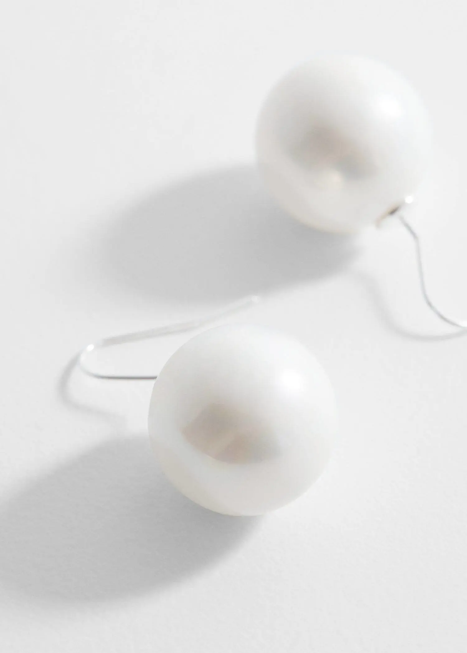 Mango Pearl crystal earrings. a pair of white balls sitting on top of a table. 