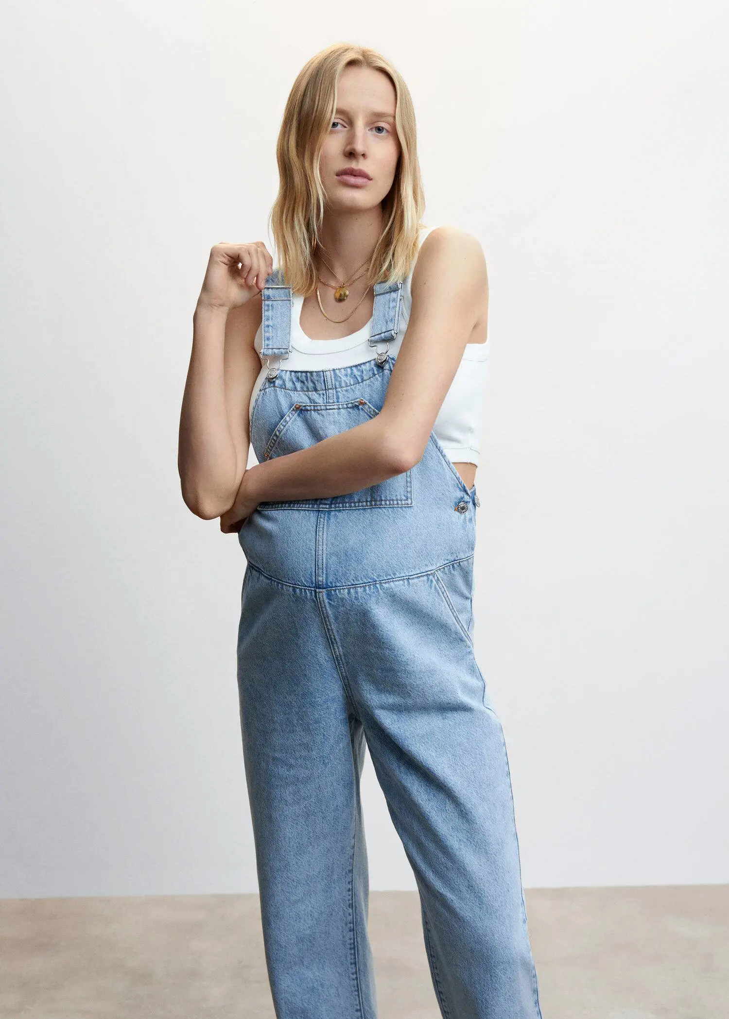 Mango Maternity denim dungarees. a woman wearing a white shirt and blue overalls. 