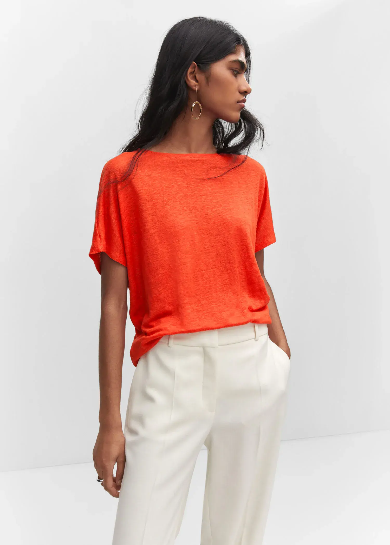 Mango Oversized linen t-shirt. a woman wearing white pants and an orange top. 