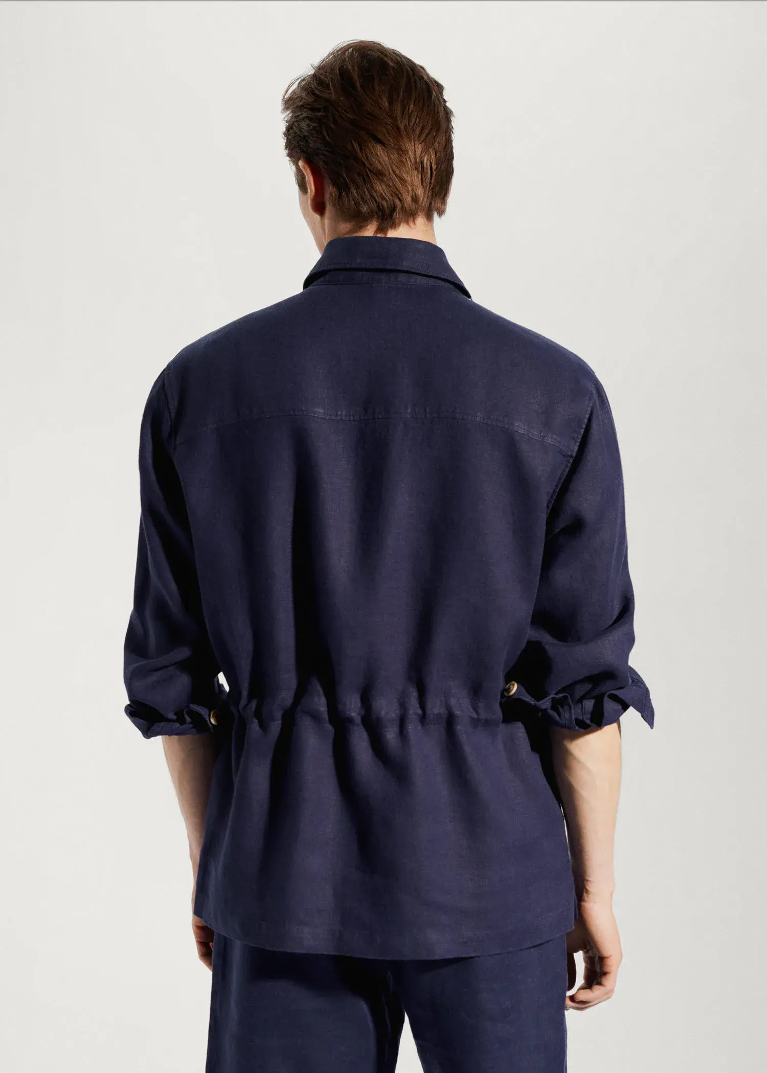 Mango 100% linen regular-fit overshirt. a person wearing a blue jacket standing next to a wall. 