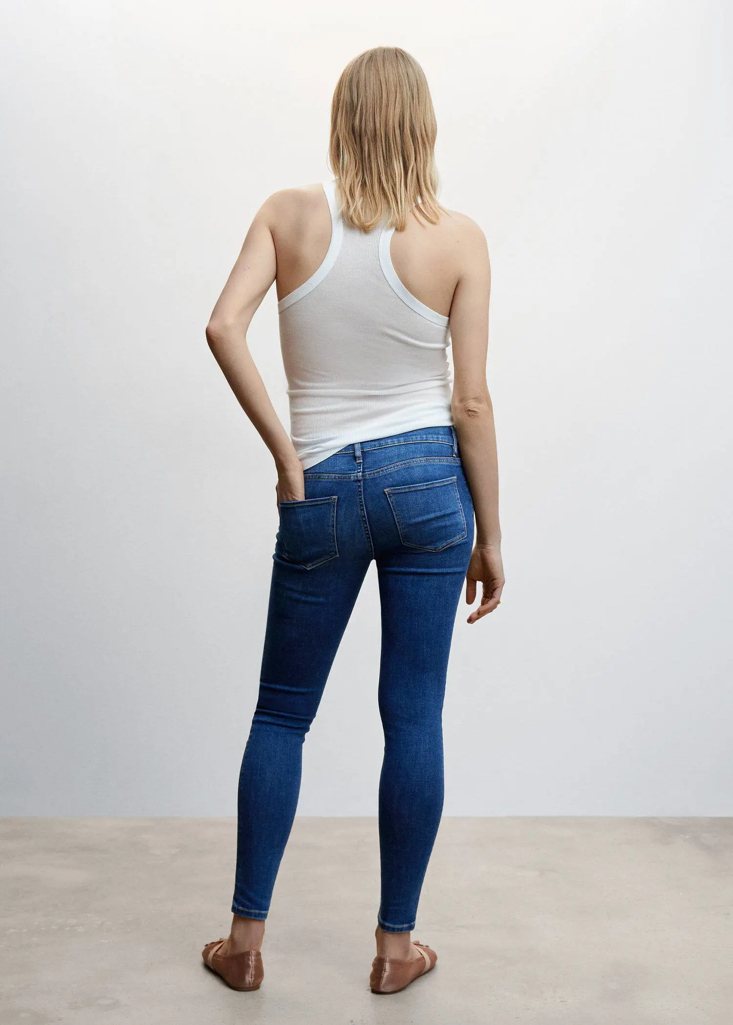 Mango Maternity skinny jeans. a woman wearing a white tank top and blue jeans. 
