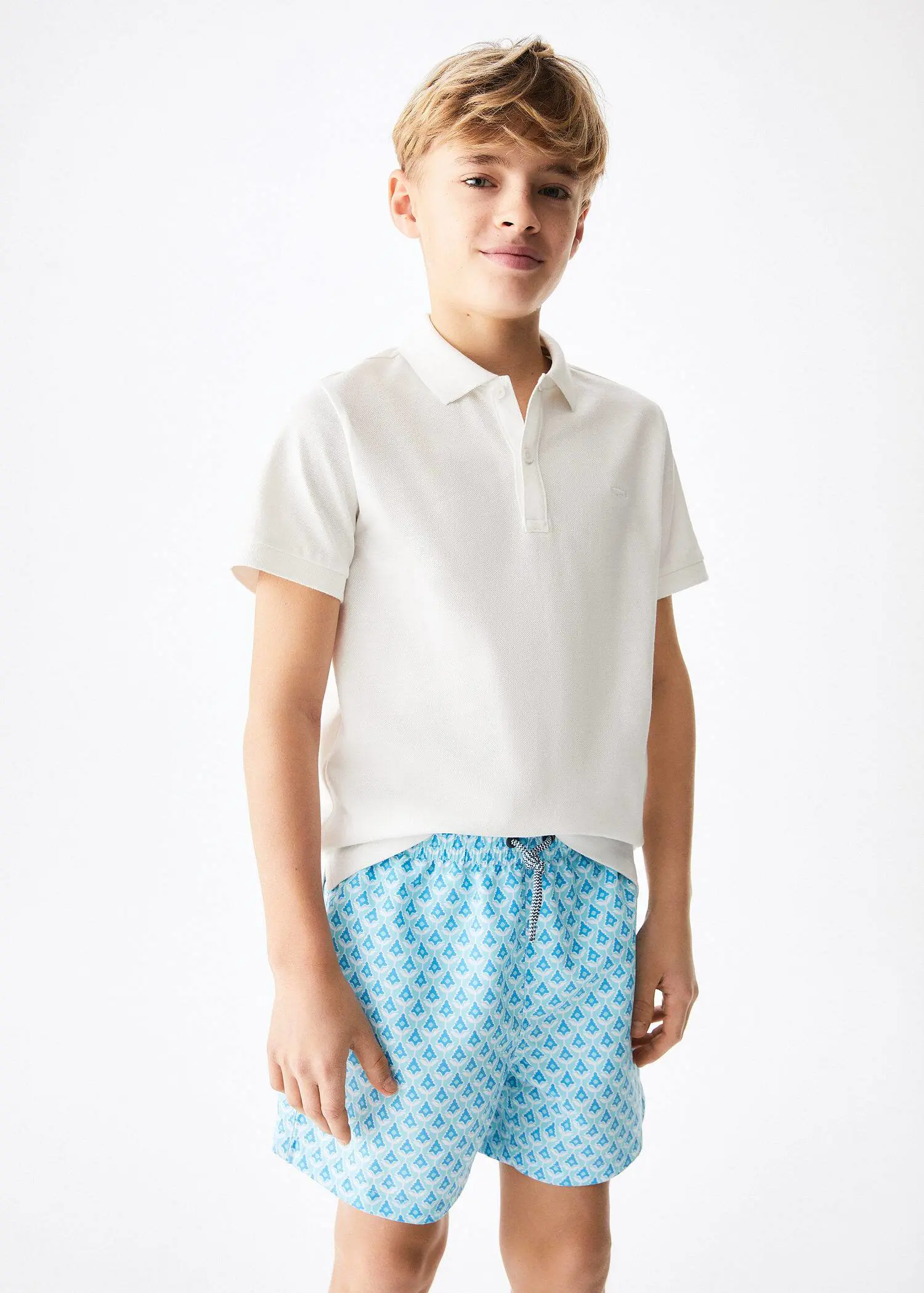 Mango KIDS/ Printed swimsuit. a young man wearing a white shirt and blue shorts. 