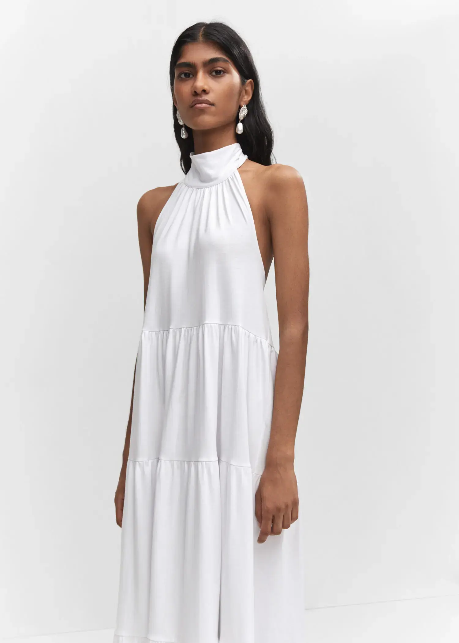 Mango Halter-neck open-back dress. a woman wearing a white dress standing in front of a white wall. 