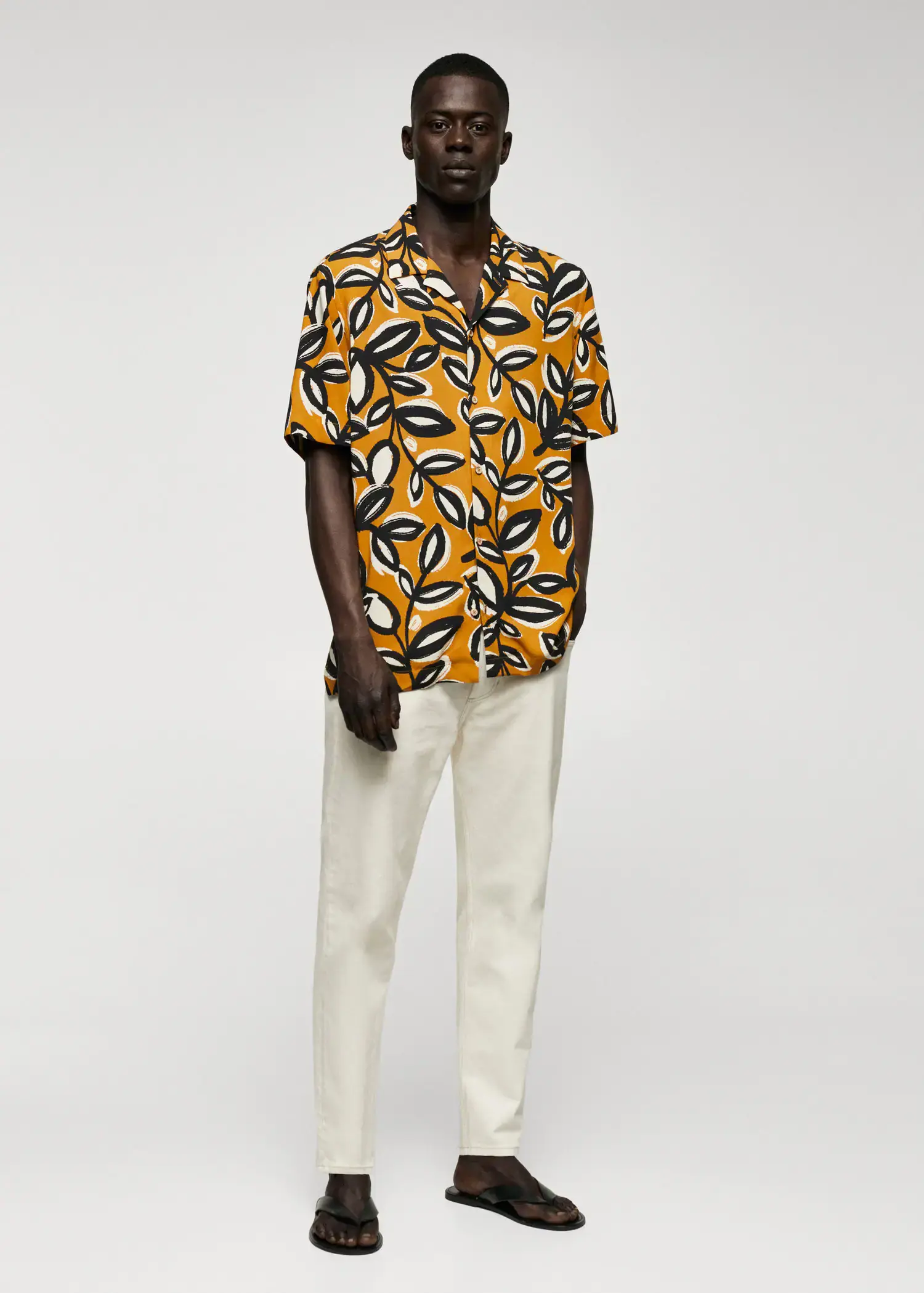 Mango Flowing leaf-print shirt. a man wearing a yellow and black shirt and white pants. 