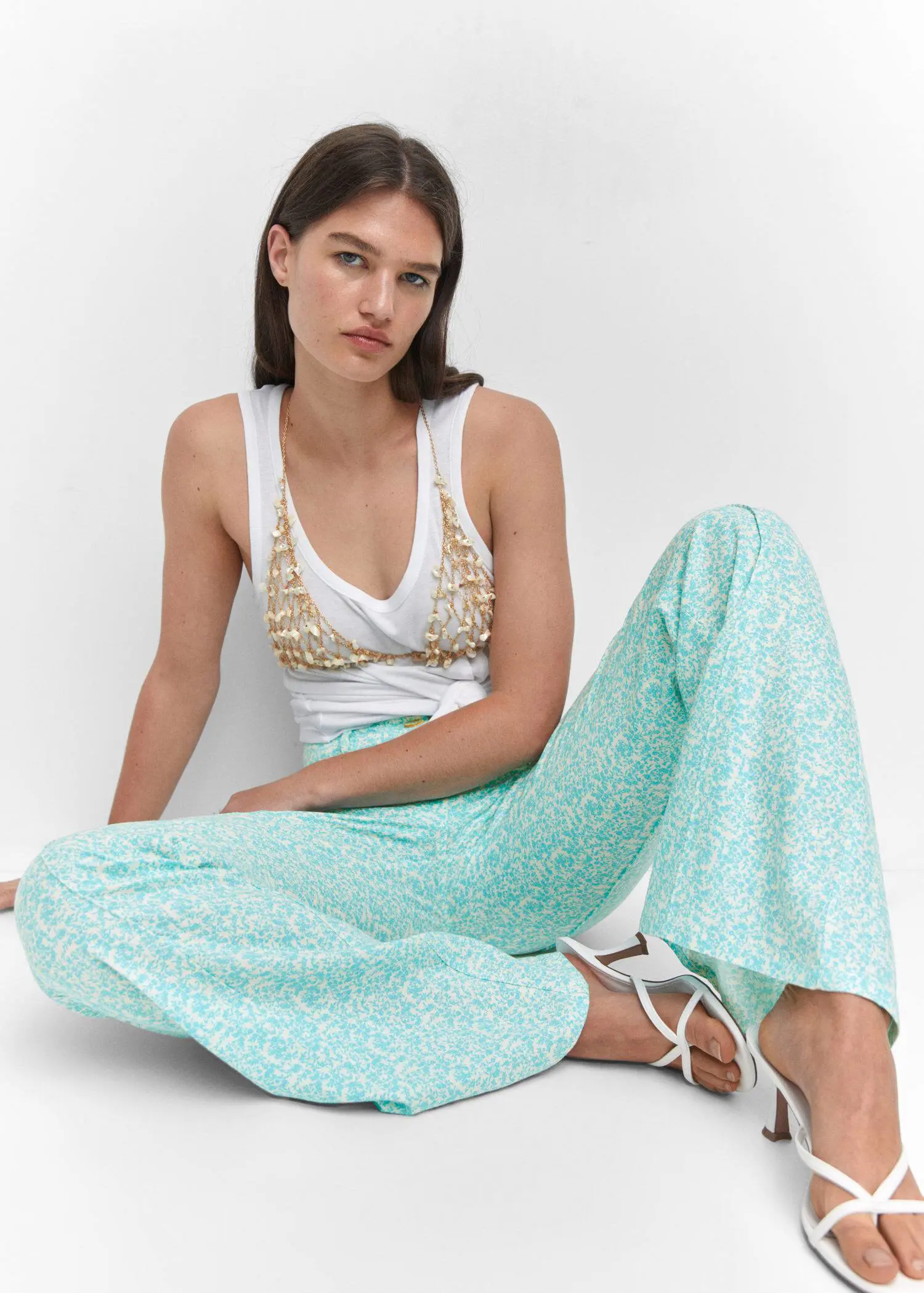 Mango Floral linen pants. a woman sitting on the ground wearing a tank top. 