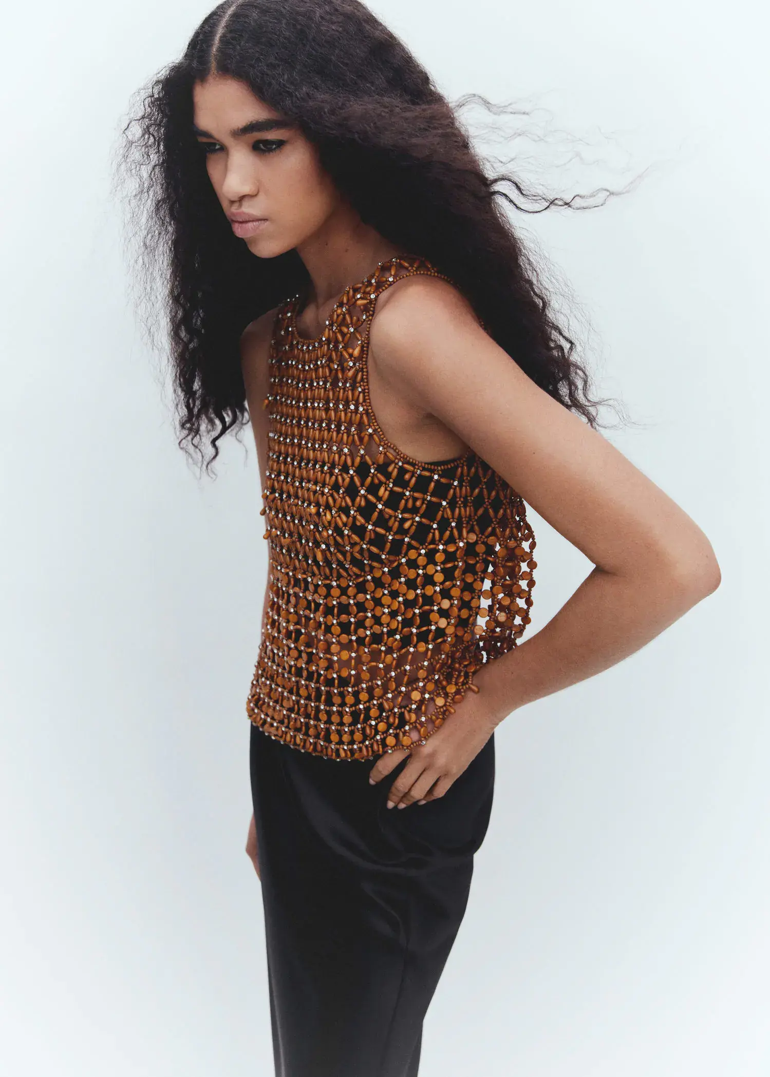 Mango Beaded open-work top. a woman with long black curly hair wearing an orange and black top. 