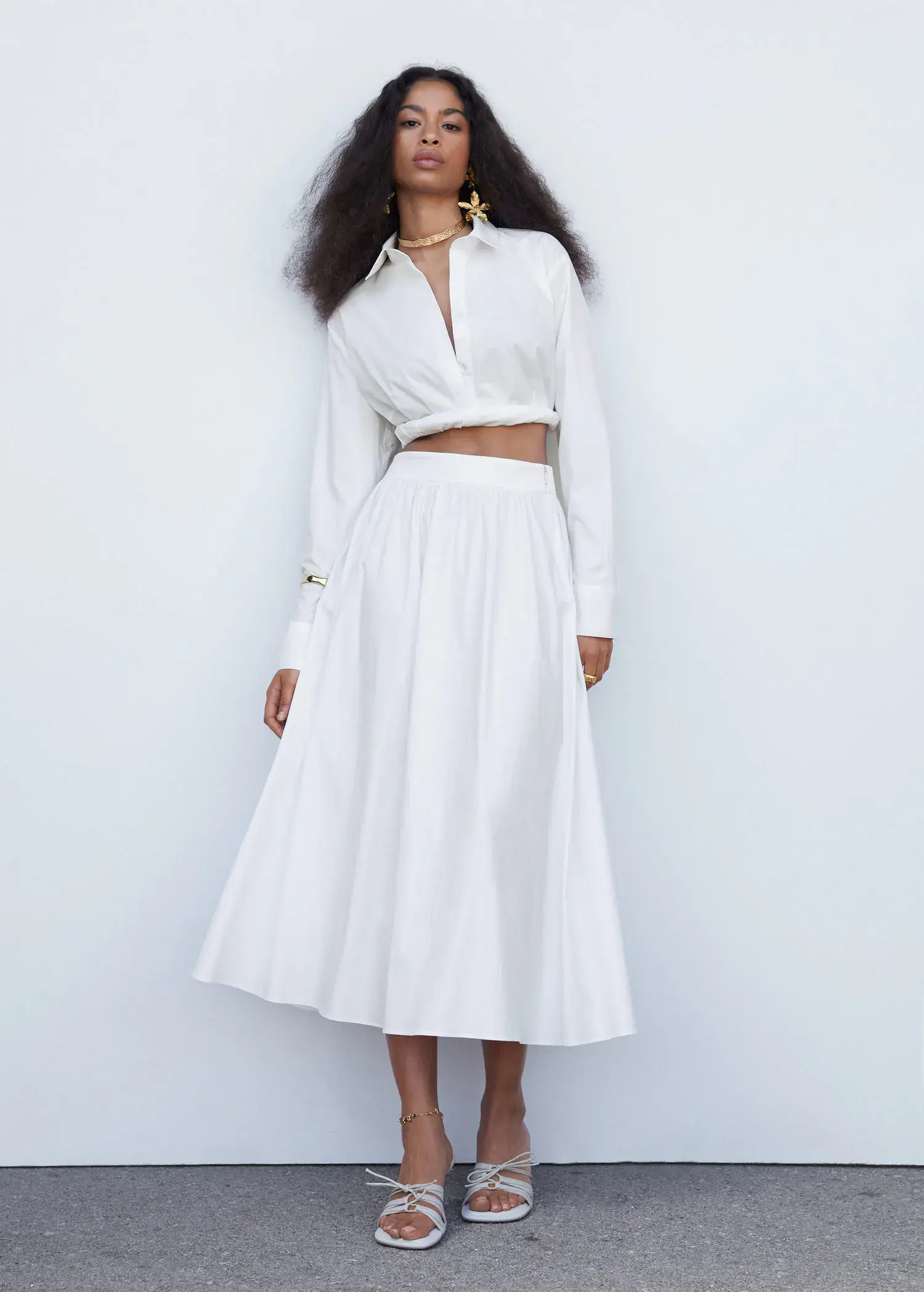 Mango Pleat detail long skirt. a woman in a white dress standing in front of a white wall. 