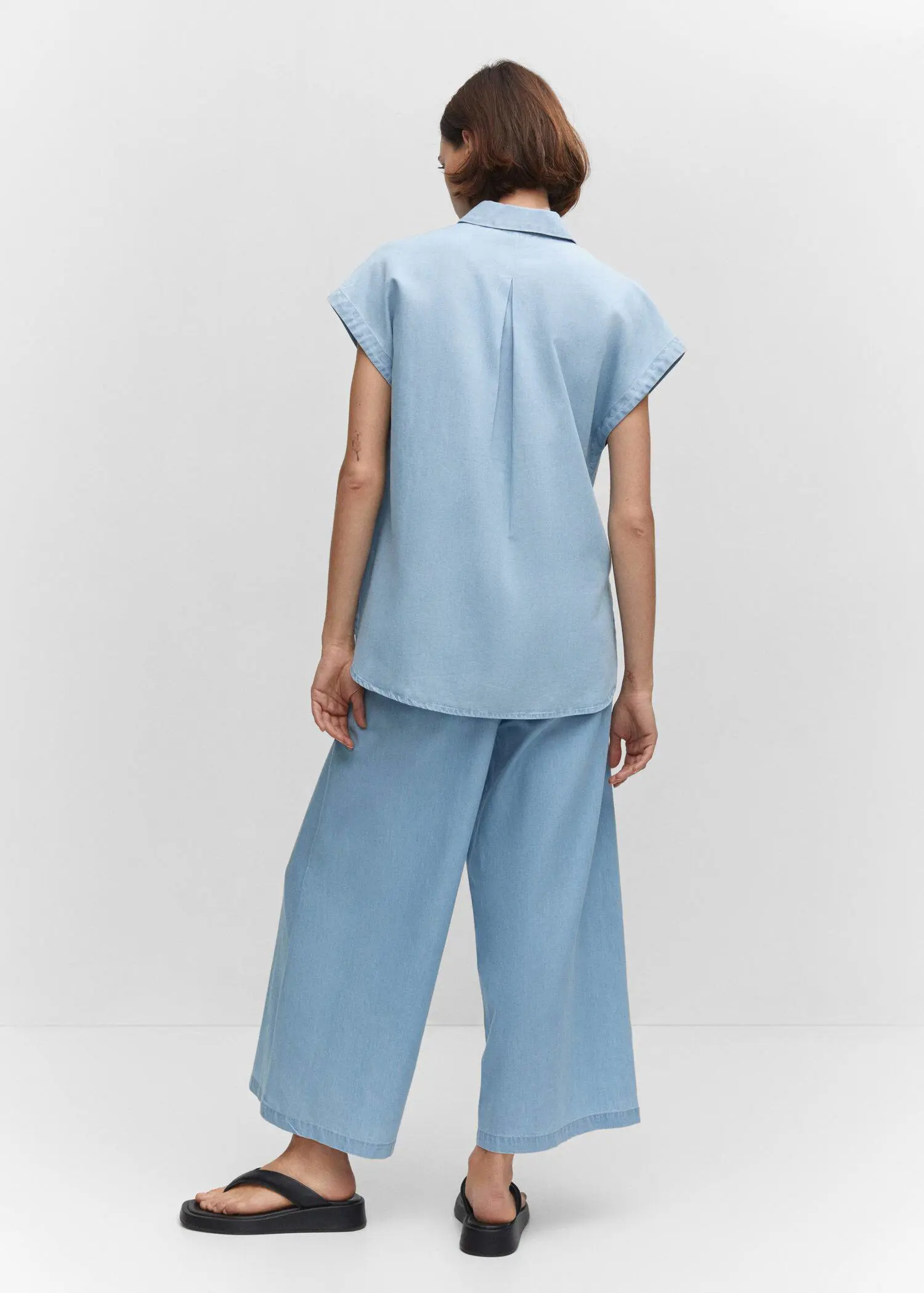 Mango Chest-pocket cotton shirt. a person standing in a room wearing a light blue outfit. 