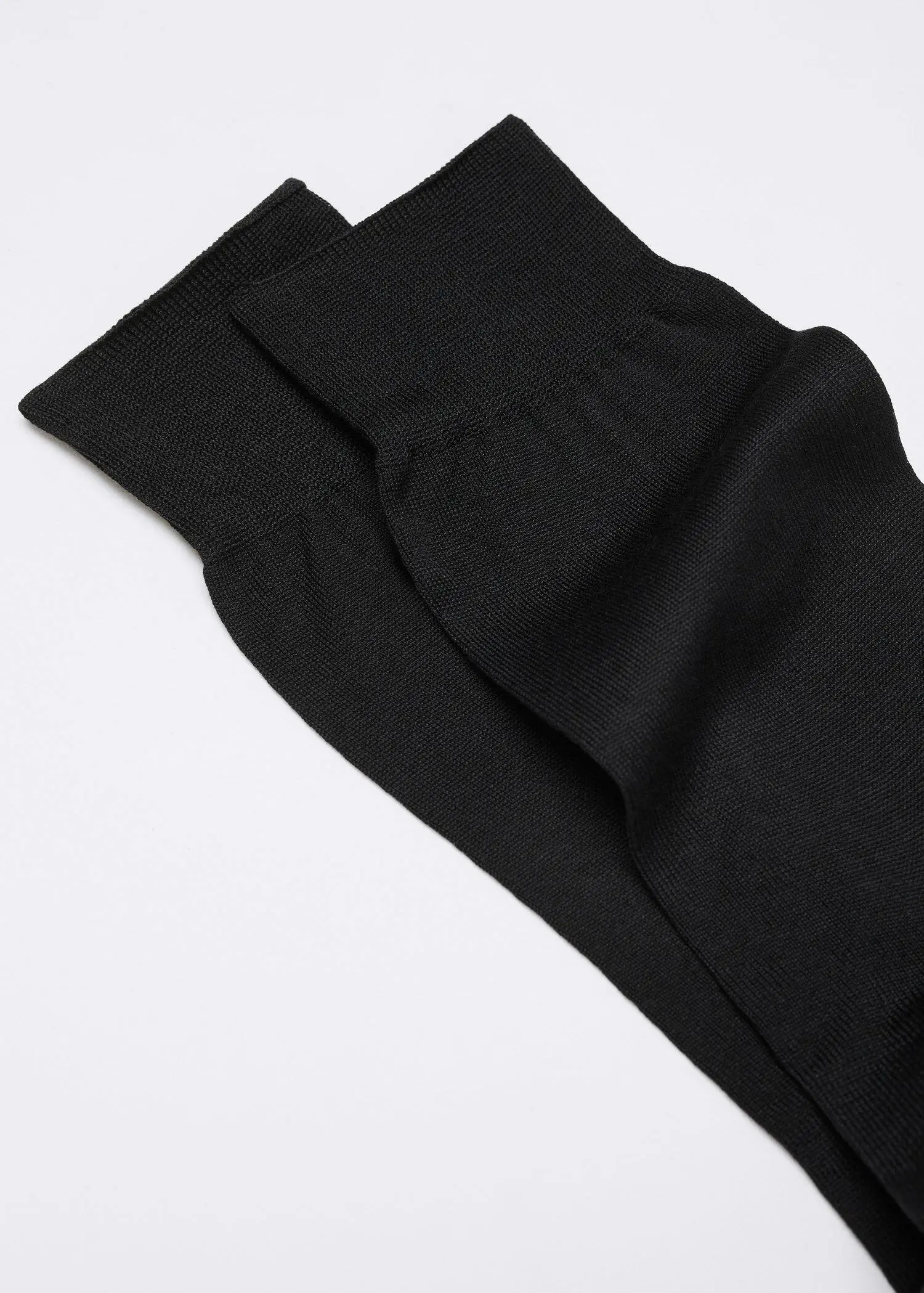 Mango 100% plain cotton socks. a pair of black socks laying on top of a white surface. 