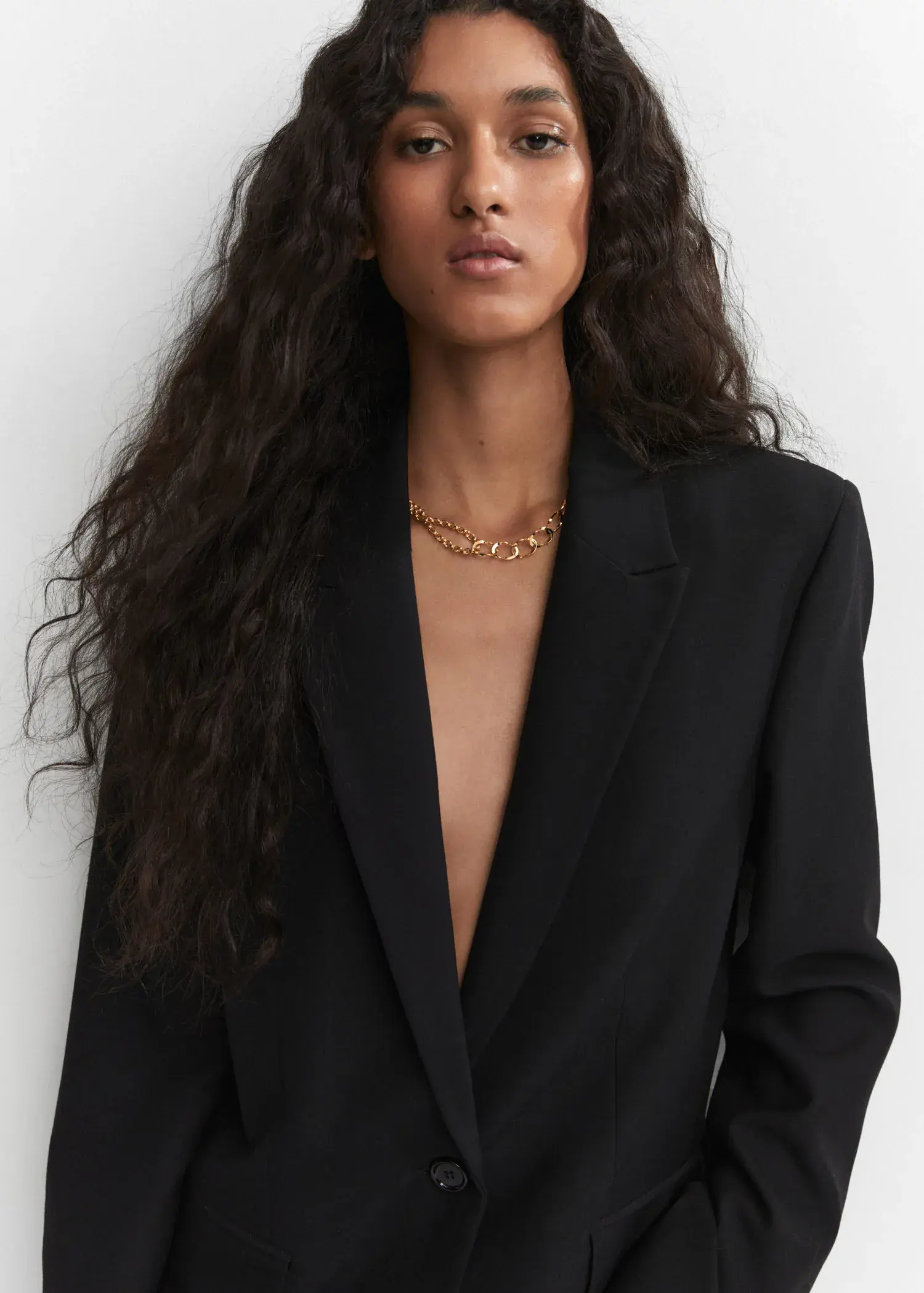 Mango Asymmetrical link necklace. a woman in a black suit and a gold chain. 