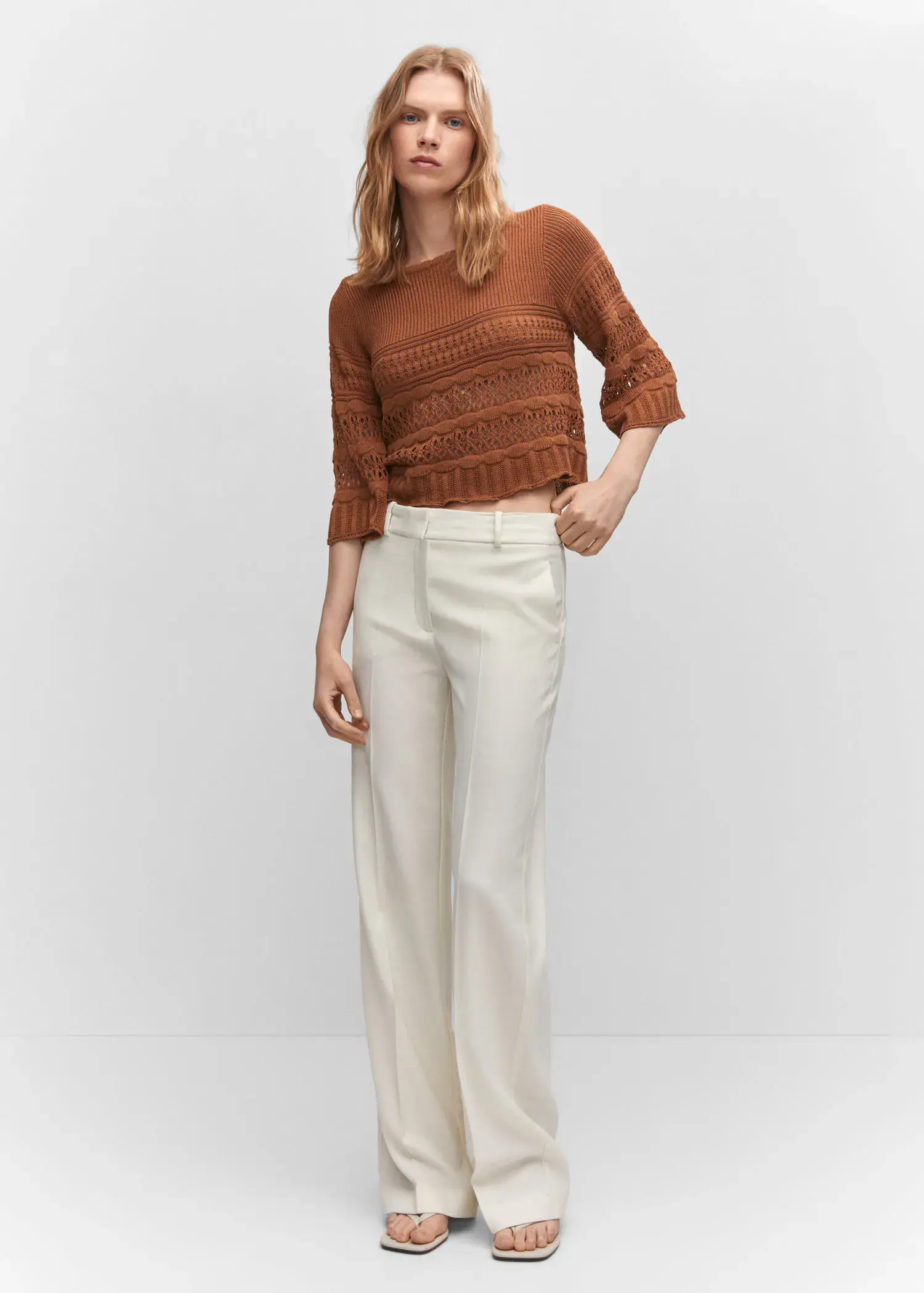 Mango Openwork sweater with flared sleeves. a woman standing in front of a white background. 