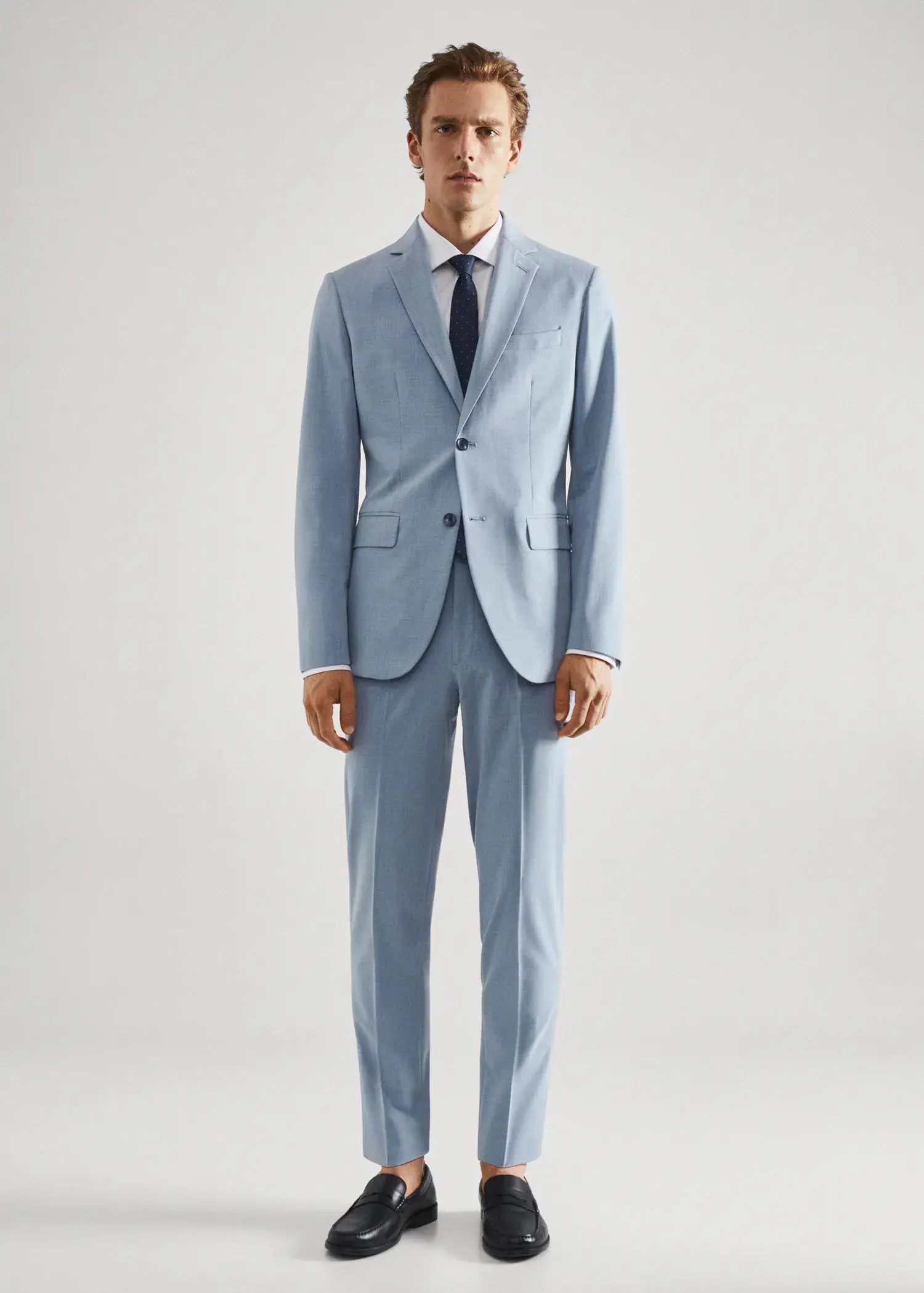 Mango Stretch fabric slim-fit suit jacket. a man wearing a suit and tie standing in front of a white wall. 