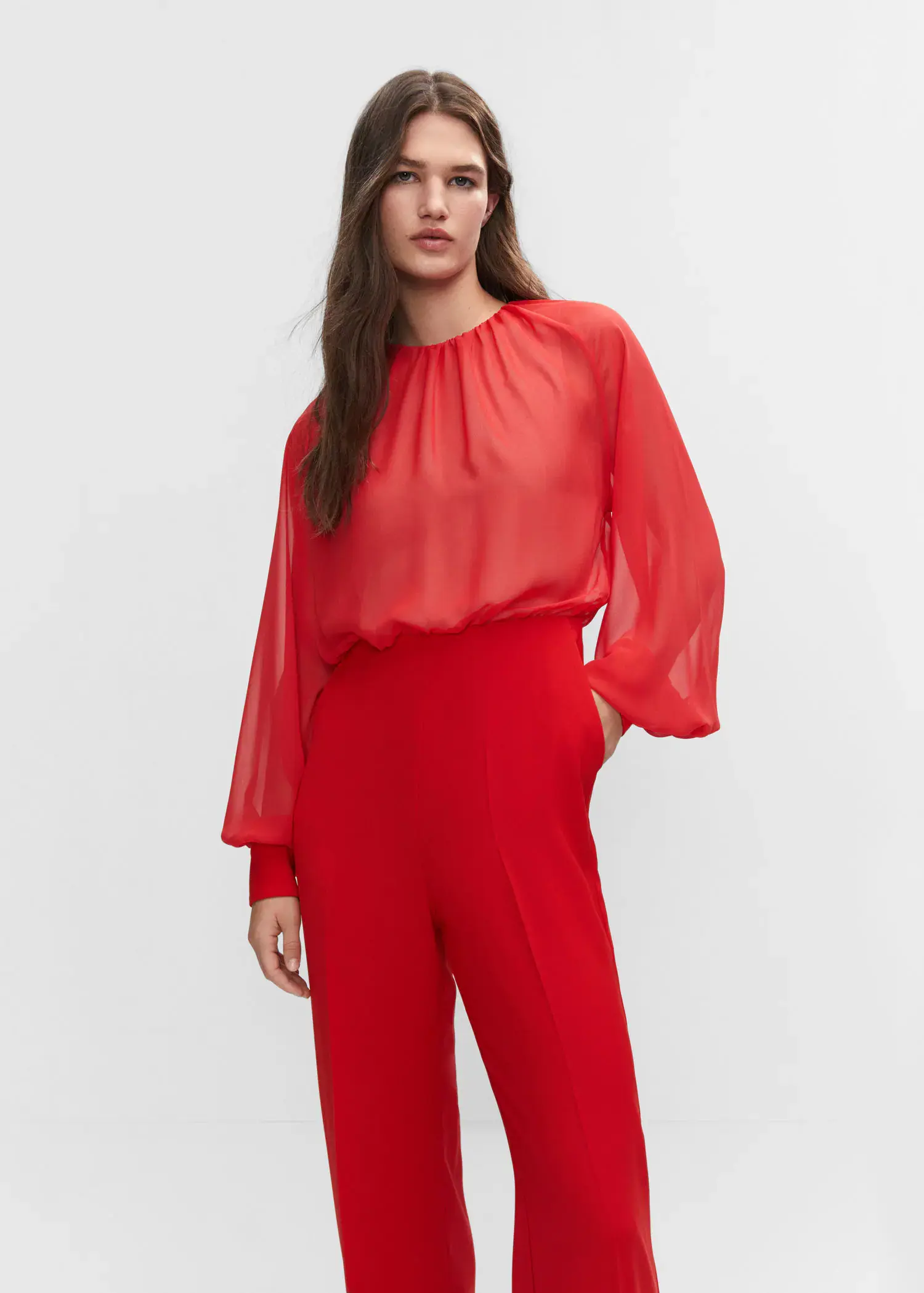 Mango Semi-transparent chiffon jumpsuit. a woman in a red outfit standing in front of a white wall. 