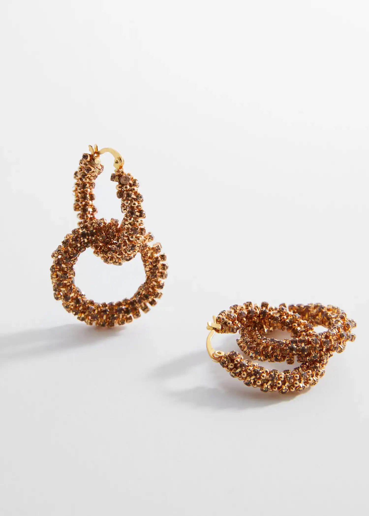 Mango Intertwined hoop earrings. a pair of earrings and a ring on a table. 