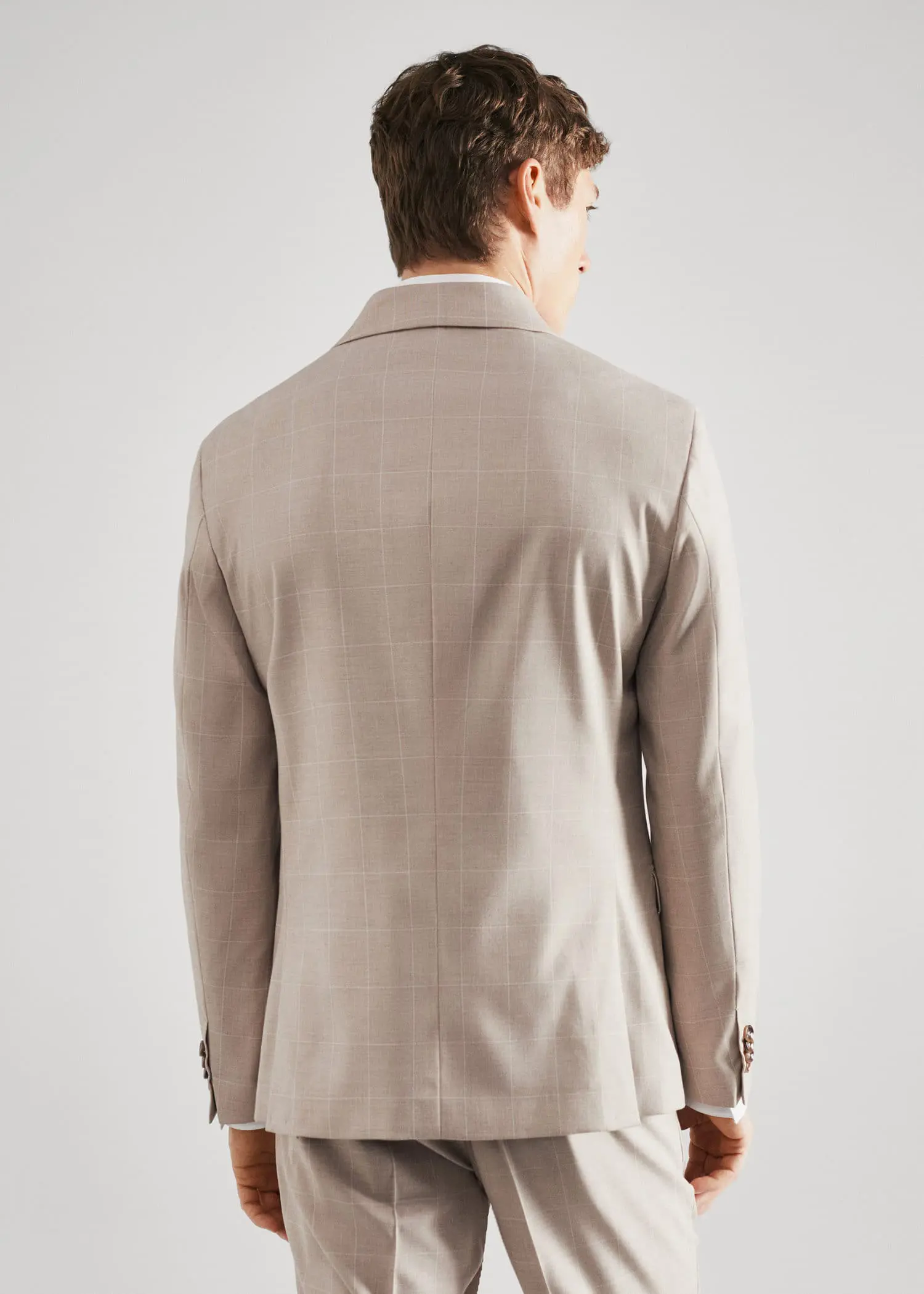 Mango Super slim-fit check suit jacket. a man wearing a suit standing in front of a white wall. 