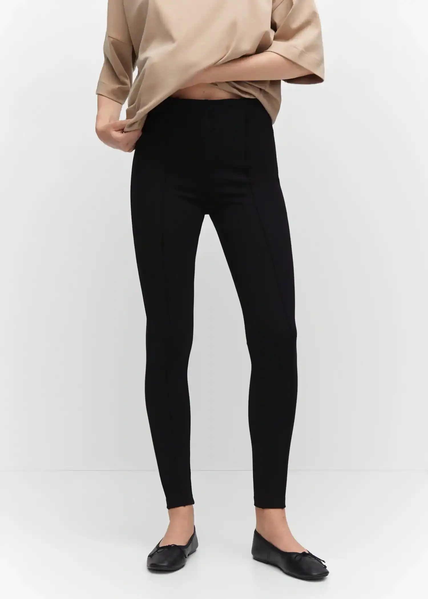 Mango Pleated skinny leggings. a person wearing black pants and a tan shirt. 