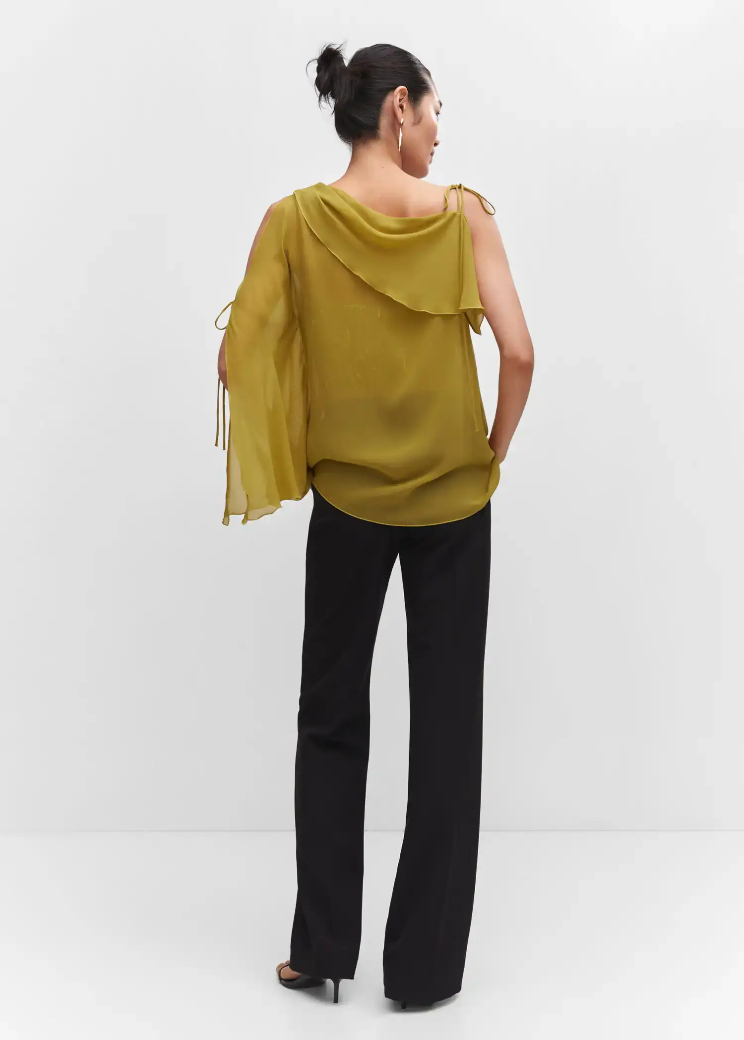 Mango Asymmetrical blouse with bows. a woman wearing a yellow top and black pants. 