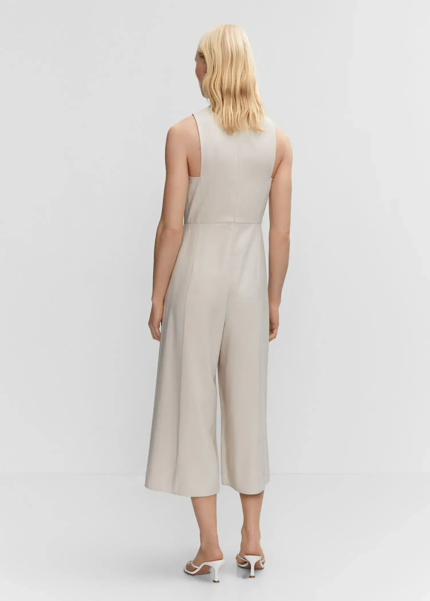 Mango Cropped jumpsuit with straps. a woman wearing a beige jumpsuit standing in front of a white wall. 