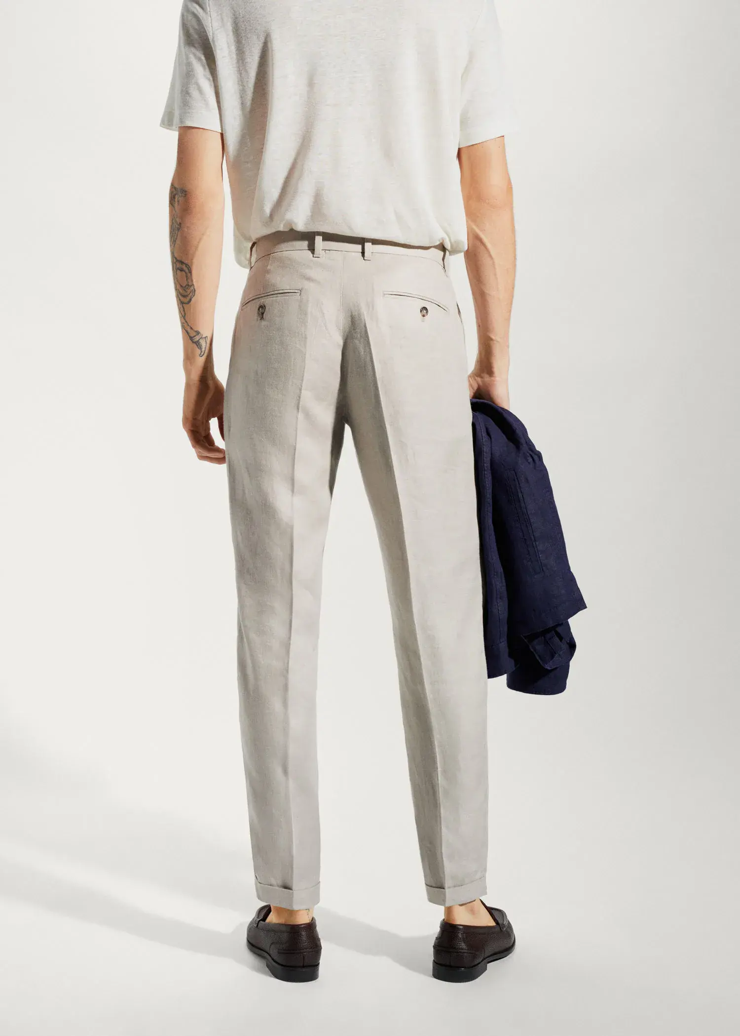 Mango 100% linen regular-fit trousers. a man in a white suit is holding a jacket. 