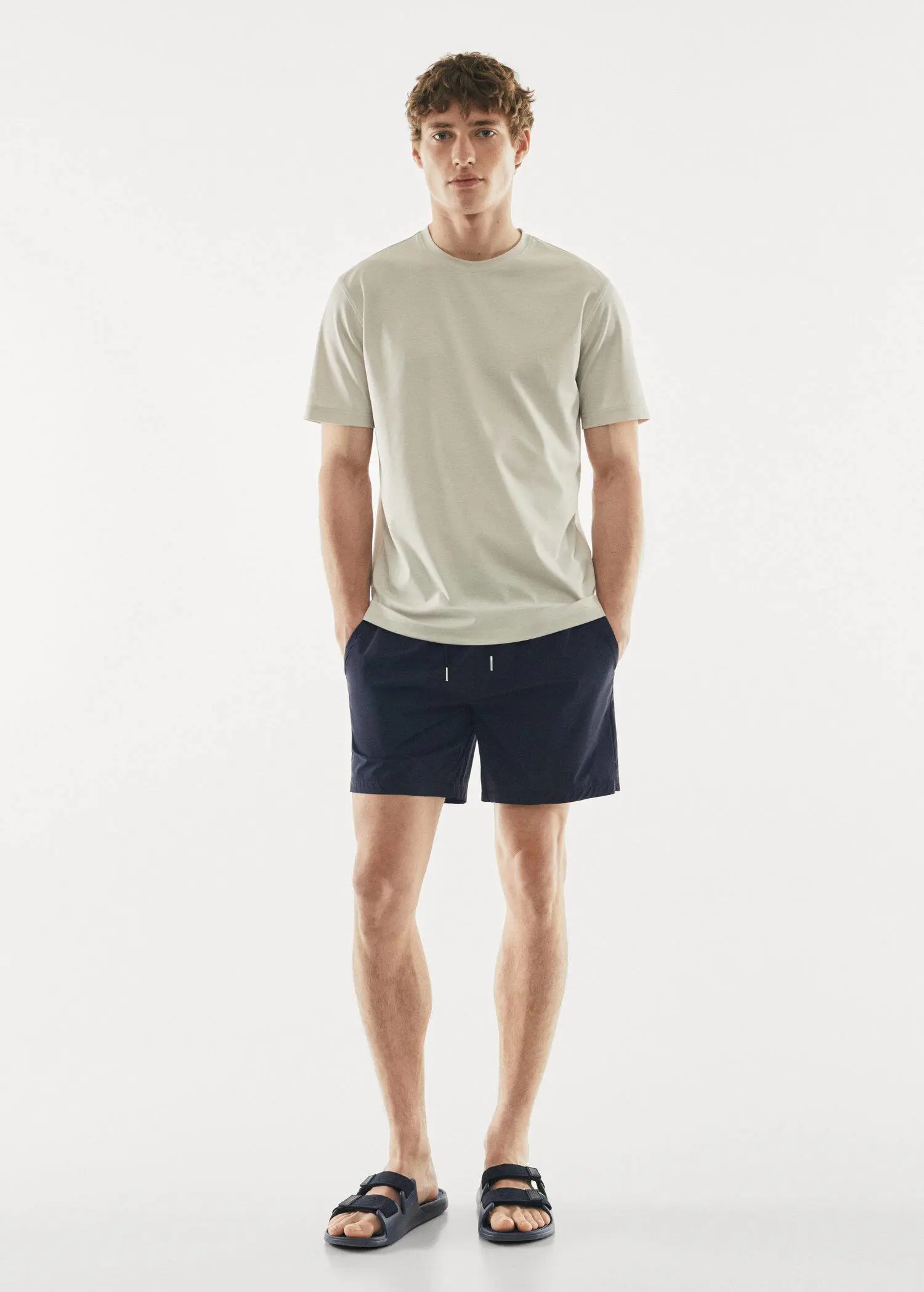 Mango Cord plain swimming trunks. a young man in a white t-shirt and black shorts. 