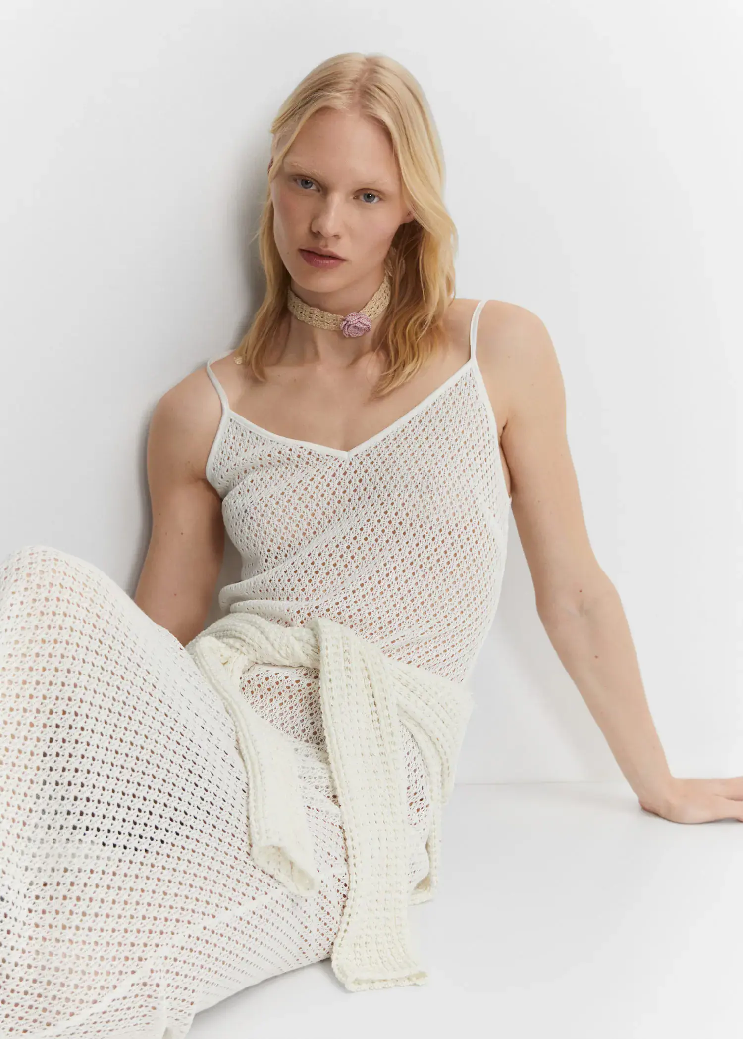 Mango Long openwork knitted dress. a woman sitting on the ground wearing a white outfit. 