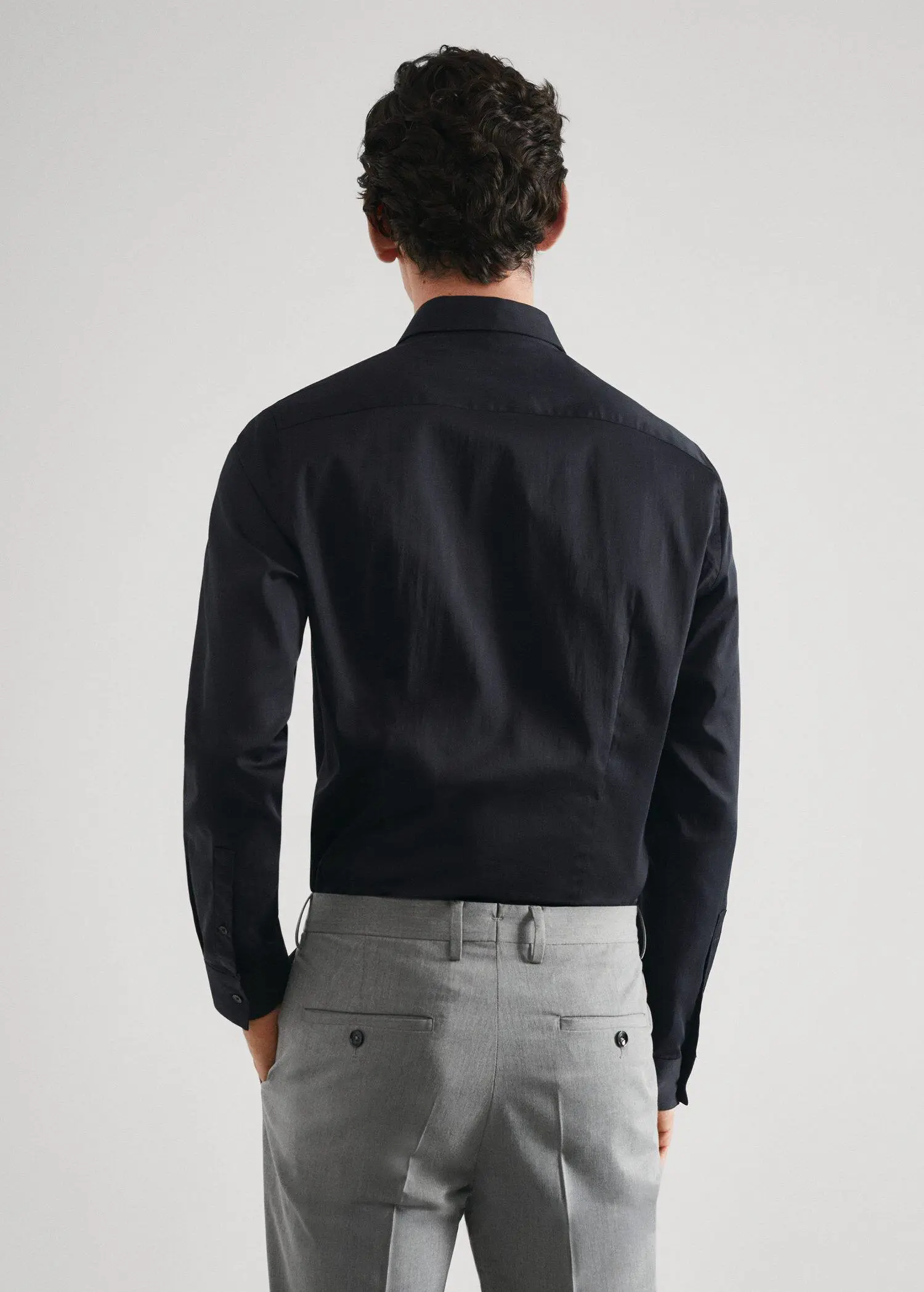 Mango Super slim-fit poplin suit shirt. a man wearing a black shirt and gray pants. 