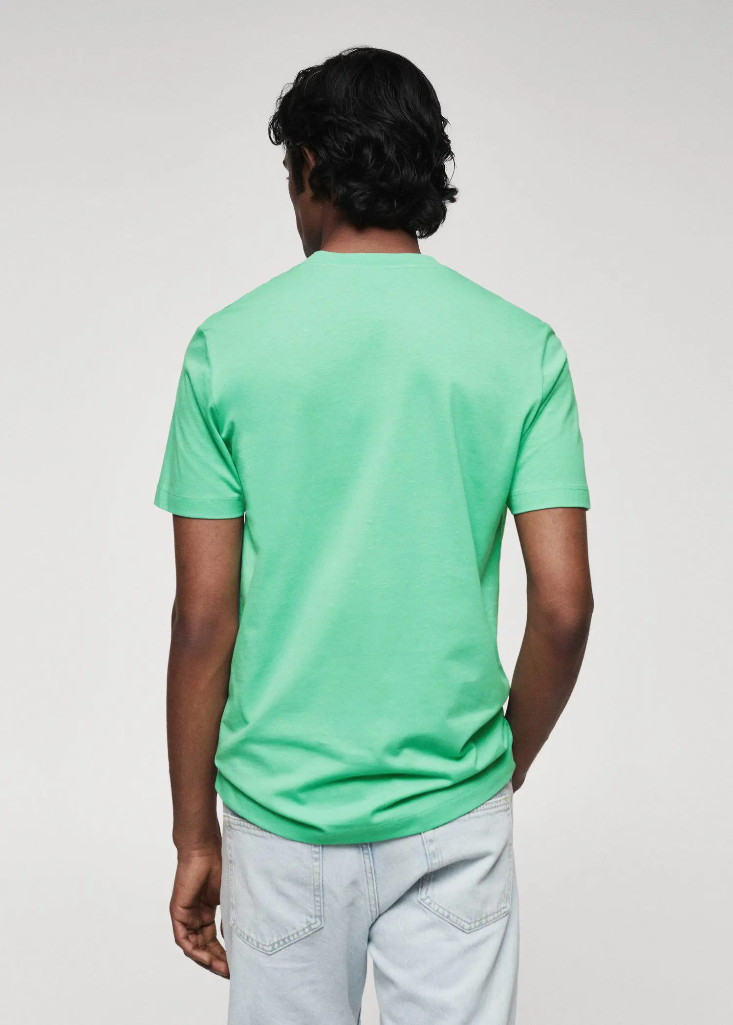 Mango 100% cotton V-neck t-shirt . a man in a green shirt is standing with his hands in his pockets. 